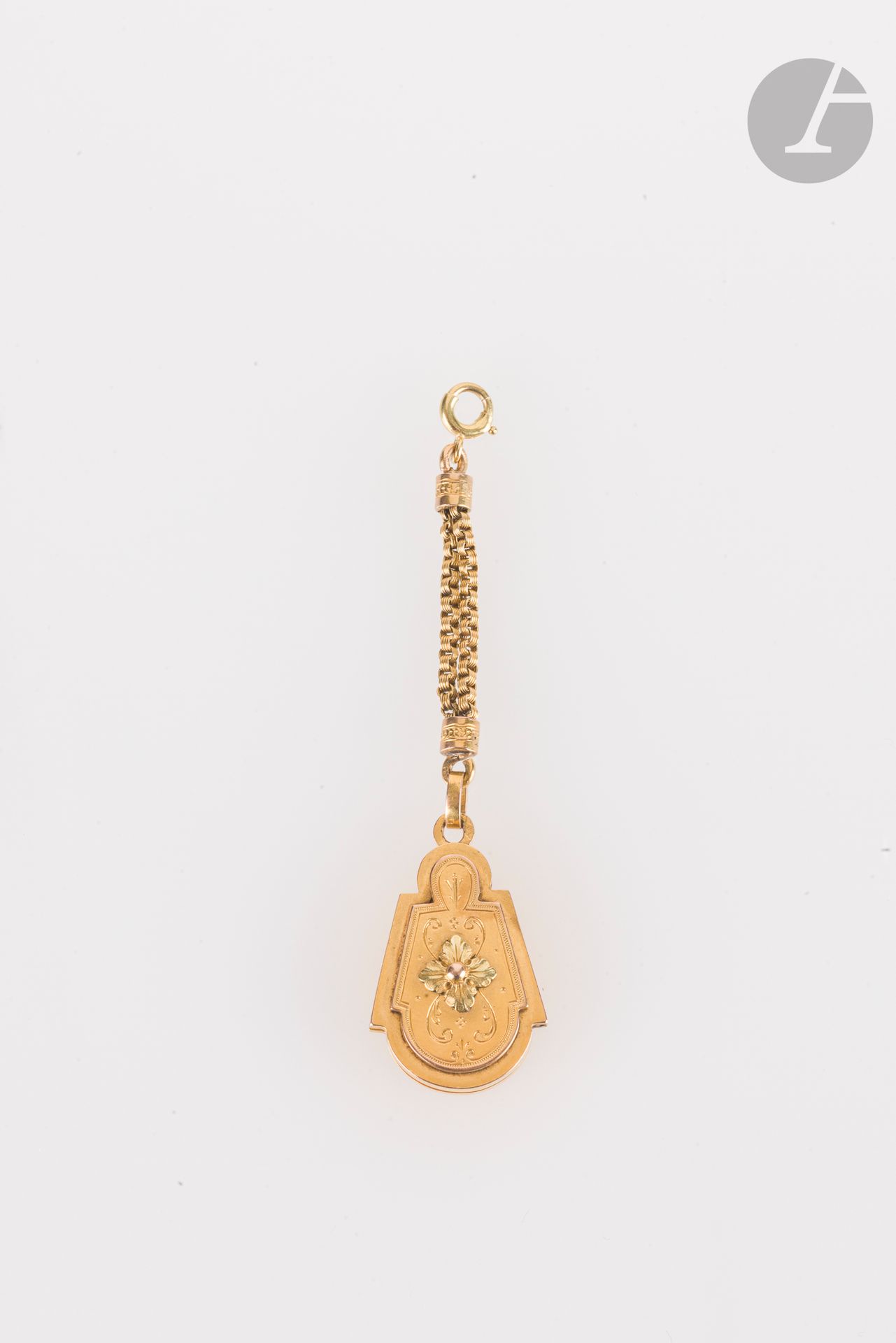 Pendentif-médaillon porte-souvenir en or 18K (750), muni d'une chaînette de suspension en or 18K, recélant une glace. Hauteur : 2,5 cm environ. Poids brut : 9,4 g
