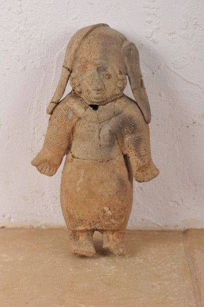 Femme debout vêtue d’une jupe longue et richement parée. Terre cuite beige à décor en pastillage et rehauts de peinture rouge. Traces de brûlure et d’oxyde de manganèse. Jama-Coaque, Province de Manabi, Équateur, 500 av. - 500 ap. J.-C. H : 25,5 cm - l : 14,5 cm - 8 cm État : cassé et recollé avec petit manque.