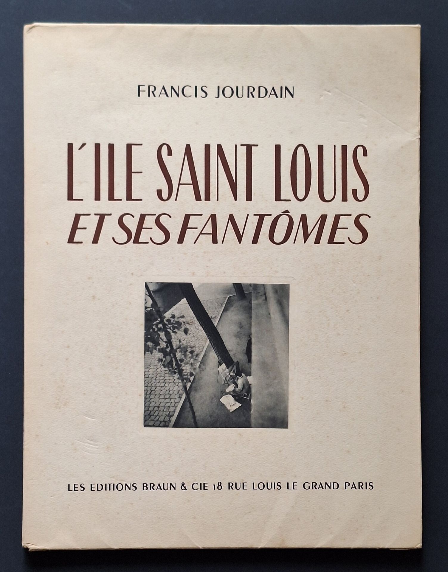 DUVAL, RÉMY (1907-1984)
L'île Saint Louis et ses fantômes.
Les Éditions Braun & Cie, Paris, 1946.
In-folio (37 x 28 cm). Édition originale, tirée à 750 exemplaires numérotés. Exemplaire n°435. Texte de Francis Jourdain. Photographies de Rémy Duval. 20 pp. de texte, suivies de 15 photographies reproduites en héliogravure, encrées à la main à l'unité. Cartonnage rigide sous jaquette illustrée rempliée. Intérieur du livre en parfait état ; pages de garde et couvertures avec de rares rousseurs.
Rémy Duval a été l'assistant de Laure Albin-Guillot.