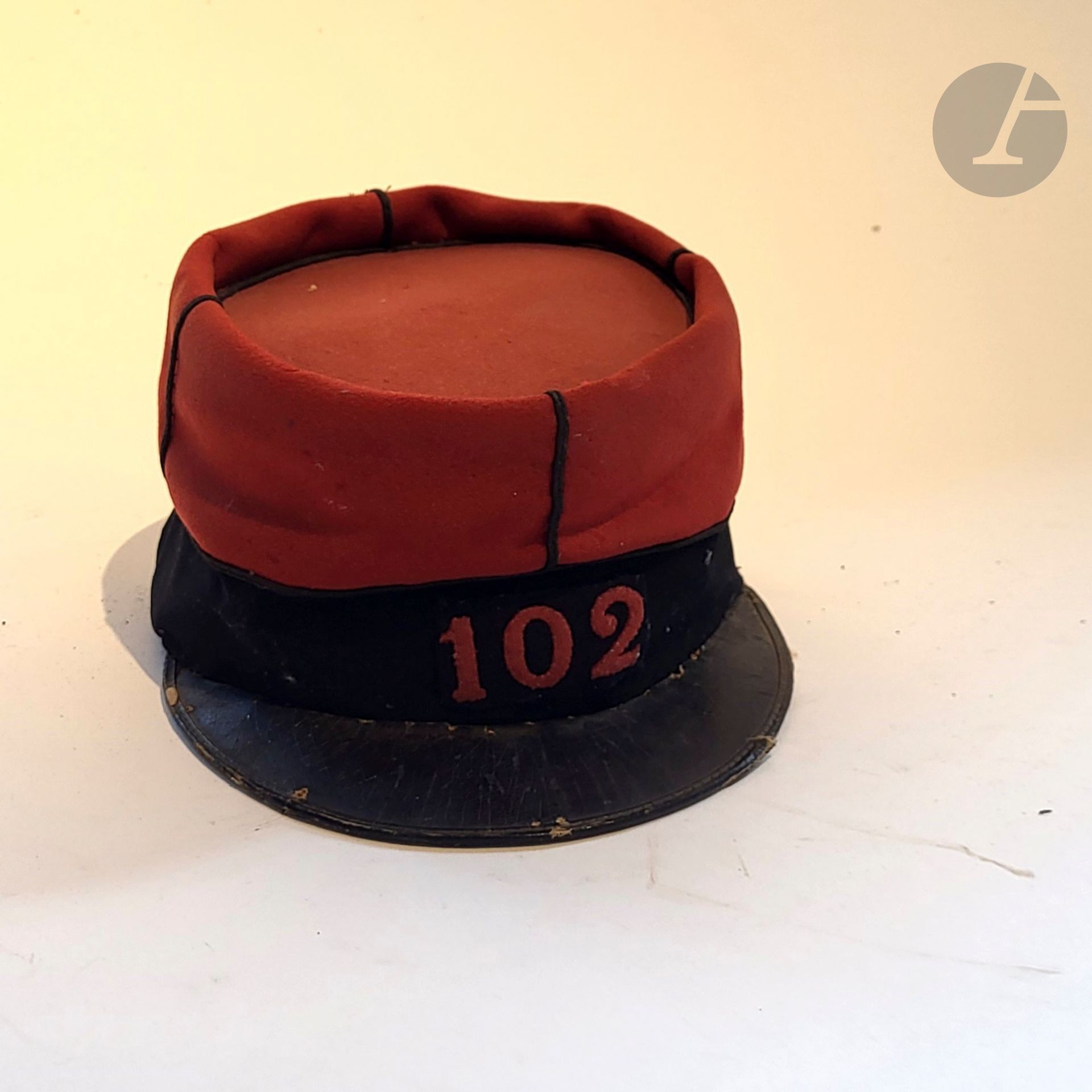 Képi du 102e de ligne. 
Bandeau en drap noir avec motif au chiffre découpé écarlate « 102 » (type 1884). Turban en drap écarlate à soutaches noires. Visière en cuir. Sans boutons, ni jugulaire. Coiffe intérieure en cuir brun et satinette noire. 
Vers 1900. 
A.B.E. (visière recousue, composite).