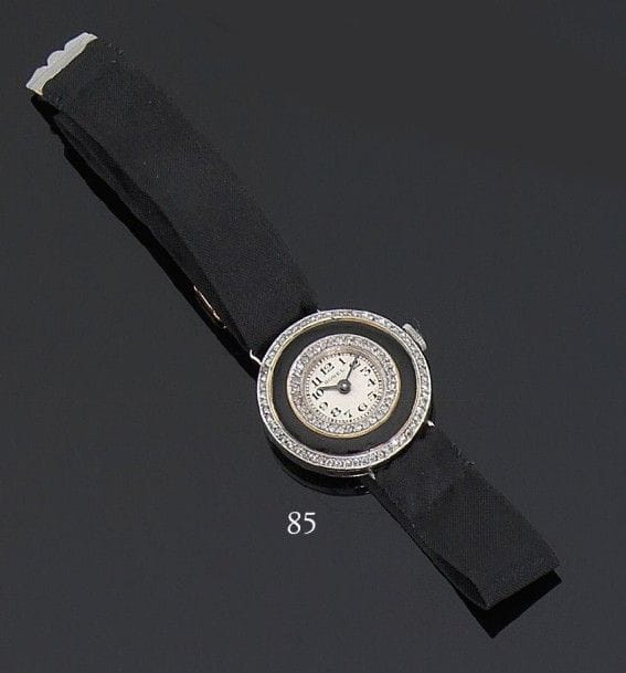 BOREL. Montre de dame en platine, cadran rond orné d’émail noir entre deux bordures serties de roses, index chiffres arabes, bracelet en ottoman de soie et ajusteur en or, mouvement mécanique. Vers 1920.Poids brut : 15,4 g (Manque la lunette, petit éclat à l’émail)