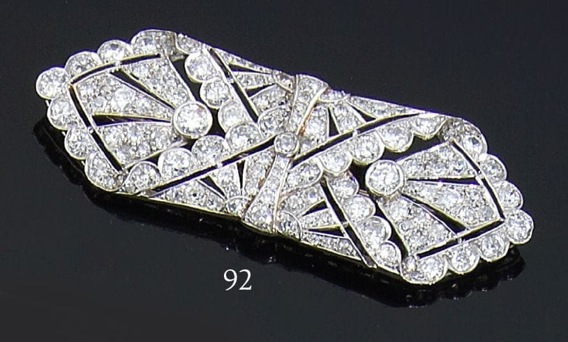 Broche Art Déco en platine, « en mouchoir plié » stylisé, ajourée de motifs géométriques imbriqués, les bords festonnés, l’ensemble serti de diamants. Travail français. Années 30.Poids : 17,9 g