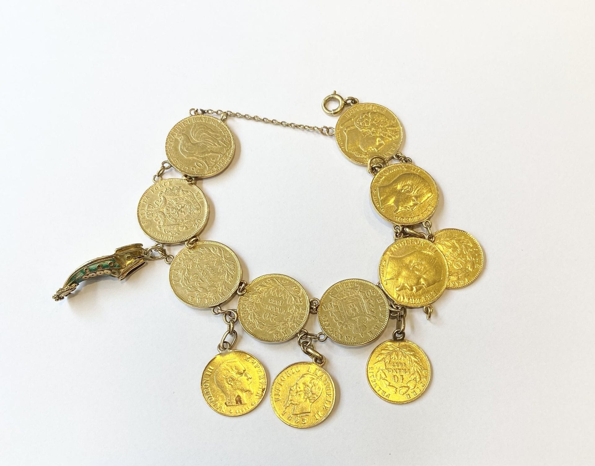 Bracelet en or jaune 750/°°° serti de 12 pièces en or. 
- 4 pièces de 20 Francs or Napoléon III tête nue 1855, 1857, 1859. 
- 1 pièce de 20 Francs or Napoléon III tête laurée 1866. 
- 1 pièce de 20 Francs or Cérès 1851. 
- 1 pièce de 20 Francs or Coq 1906. 
- 1 pièce de 20 Francs or Léopold III, Roi des Belges tête nue 1875. 
- 2 pièces 10 Francs or Napoléon III tête nue 1857, 1860. 
- 1 pièce de 10 Francs Napoléon III tête laurée 1862. 
- 1 pièce de 10 lire Victor Emmanuel II 1863. 
Poids : 71,1 g
