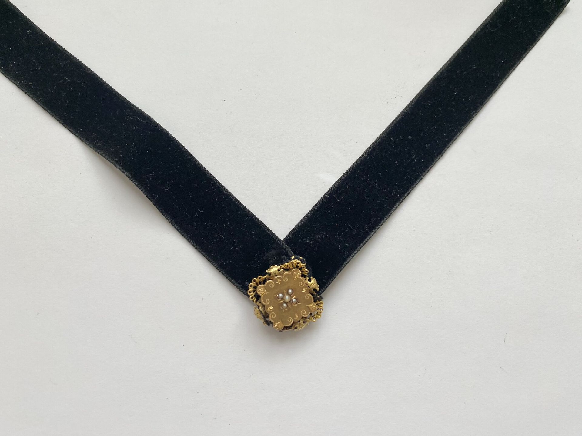 Bijoux en or jaune 750/°°° serti de quatre petites perles cousu sur ruban noir. 
Poids brut : 6 g