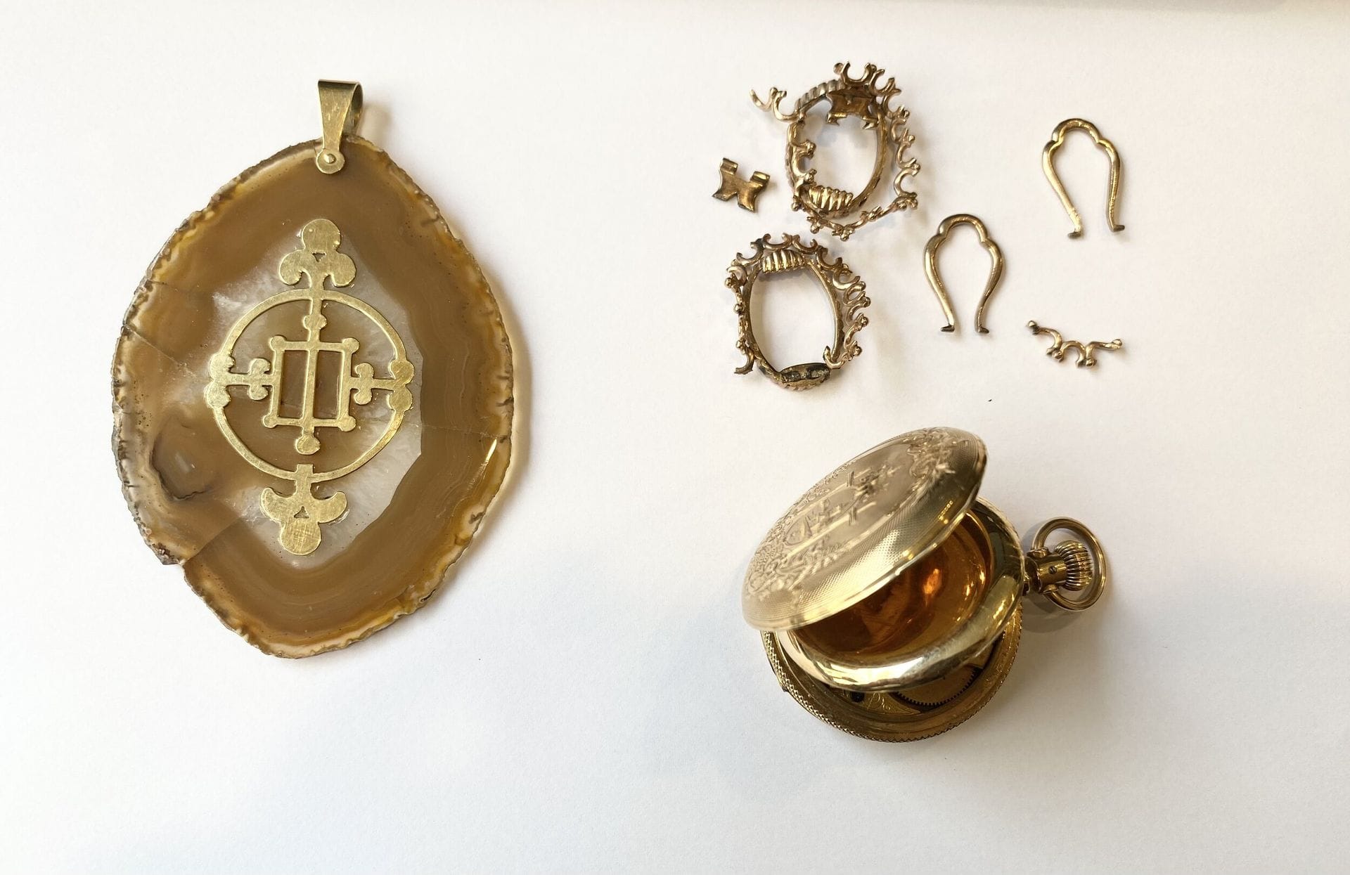 Lot d'or : 
Débris d'or 375/°° 
Poids : 11,98 g 
Pendentif tranche d agate appliqué d or 750/°°°, 
Poids brut : 37,55 g 
Montre de poche en métal guilloché, revers au décor de feuilles et arabesques. 
Signée en lettres cursives Elgin Natl Watch. 
Pois brut : 59,46 g 
Poids brut total : 110 g