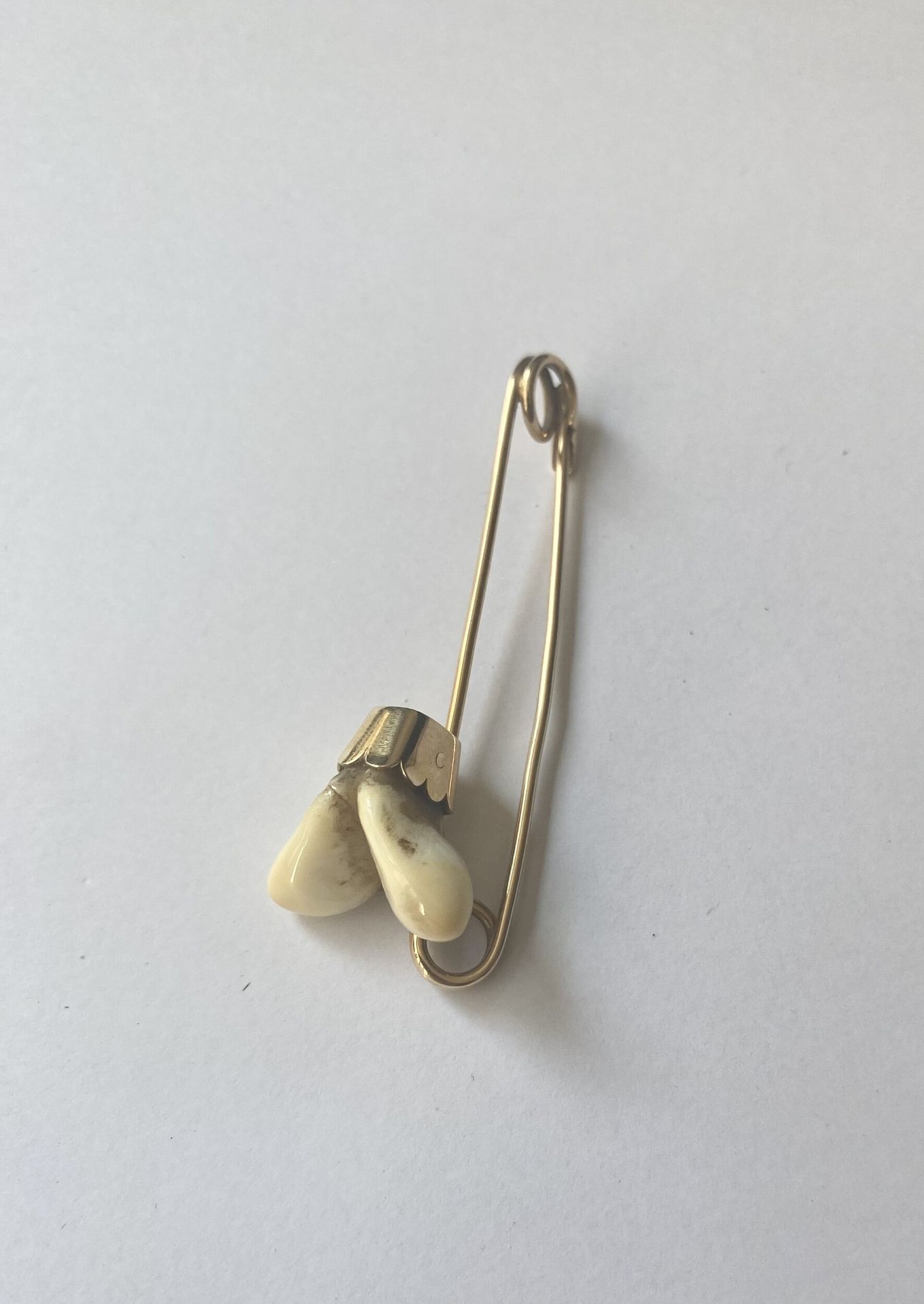 Broche cynégétique en or 750/°°° sertie de dents de cerfs. 
Poids brut : 6,6 g