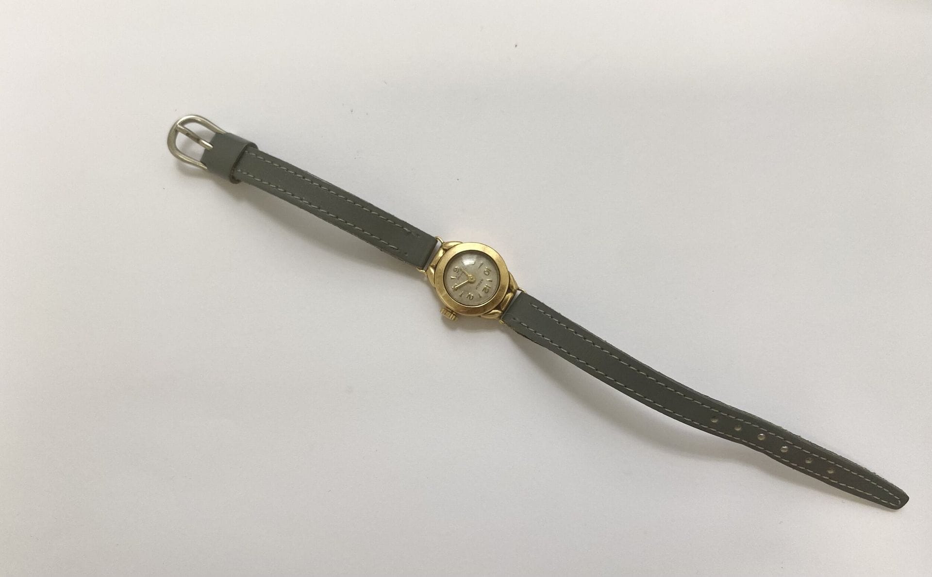 Montre Regalia de dame boitier rond en or 750/°°°. 
Bracelet cuir gris souris. 
Poids brut. : 10 g