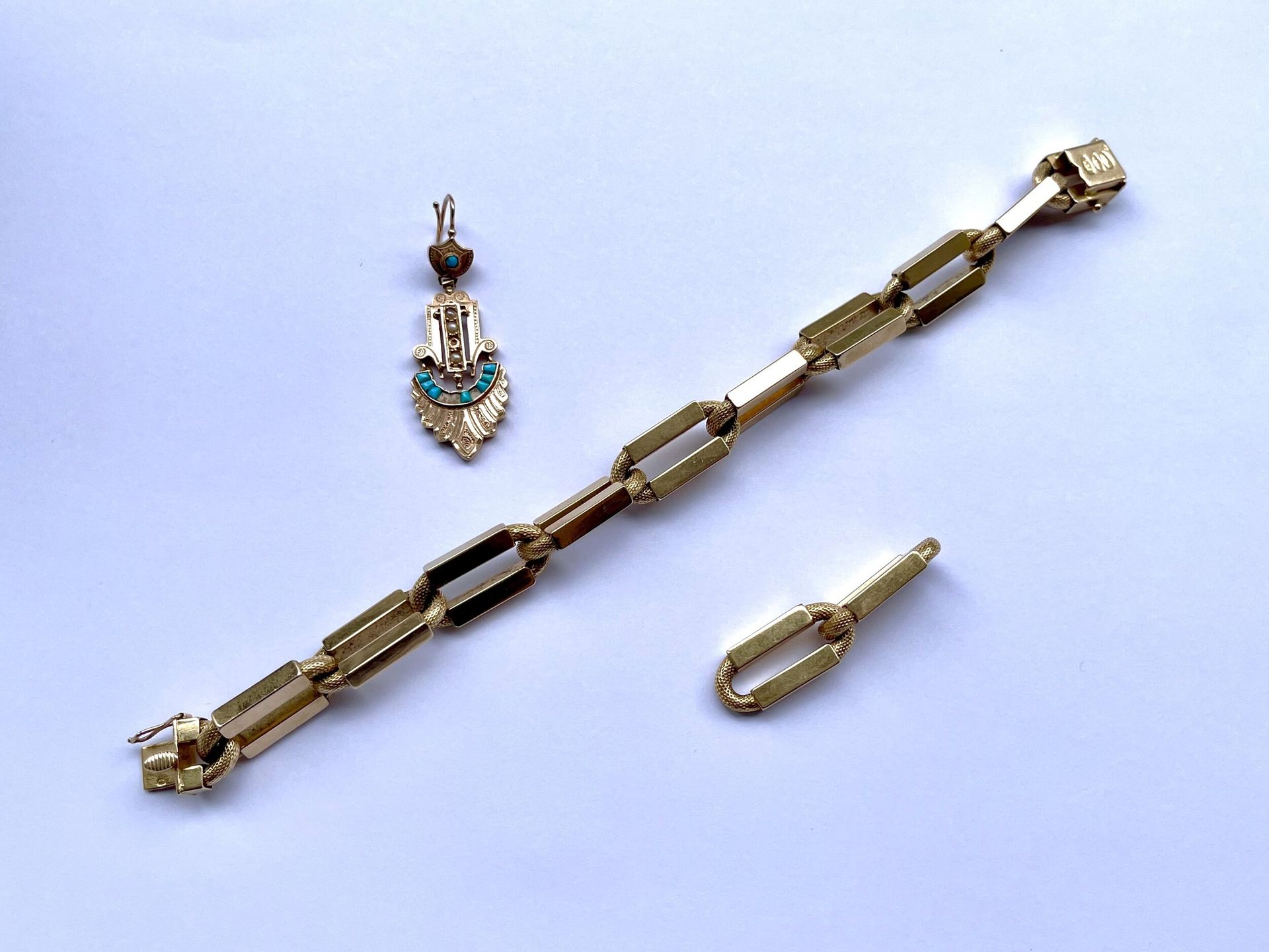 Lot en or 750/°°°: Bracelet en or 750/°°°, deux maillons à décor de mousquetons. 
Poids brut : 30.9 g 
Un pendant d oreille en or 750/°°° serti de turquoises et perles. 
Poids Brut. : 2,4 g
