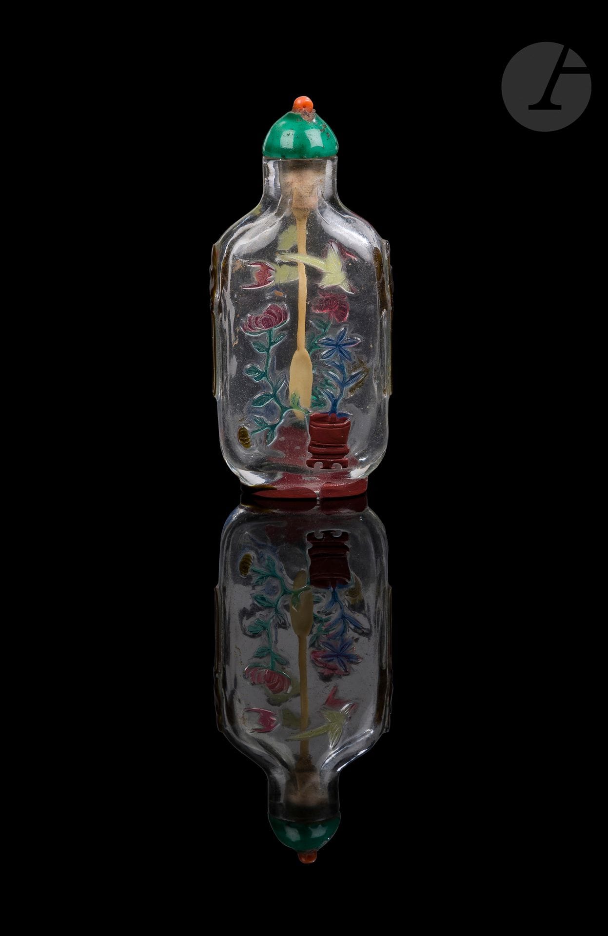 Tabatière en verre overlay six couleurs, Chine, Yangzhou, 1820-1880
De forme rectangulaire aplatie aux épaules arrondies en verre overlay six couleurs sur un fond transparent sculptée de fleurs dans une jardinière et poussant près d’un rocher percé. Au-dessus volent des oiseaux, un papillon et une chauve-souris. Des masques et anneaux en verre overlay brun ornent les épaules. Le pied est cerclé d’un overlay rouge cinabre. Bouchon en porcelaine émaillée vert imitant la jadéite surmonté d’une bille de corail.
Hauteur : 5,9 cm