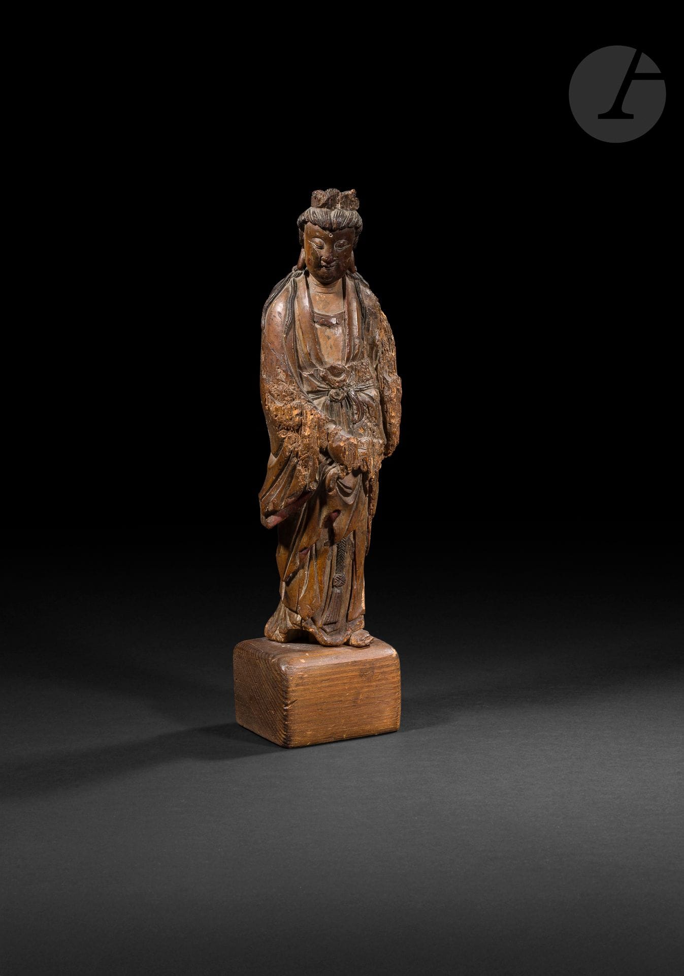 Guanyin en bois, Chine, XVIIe siècle
Représentée debout vêtue d’une longue robe à plis nouée sur le devant, tenant un pan du vêtement dans la main droite. Son visage est serein, les yeux sont mi-clos et les lobes d’oreilles tombants. Elle est coiffée d’un chignon, une mèche tressée entoure chaque oreille, puis chute sur ses épaules. Le front porte l’urna. Traces de polychromie et laque d’or. Socle.
H. (sans socle) : 28,2 cm
Manques, trous de ver et fentes.