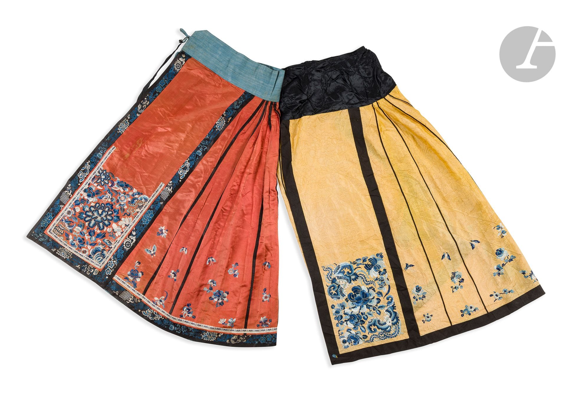 Two embroidered silk mamiamqun skirts, China, late 19th - early 20th century
- One in yellow silk damask decorated with flowers, composed of two parts with seven black braided panels sewn onto a flat black silk belt. The flat sides are decorated with a rectangular motif embroidered in blue and white silk thread with peony flowers and large butterflies, while the pleated sides are decorated with multiple small flowers and butterflies. H: 100 cm. - The other in orange silk, composed of two parts with seven gimped panels sewn onto a blue cotton belt. The flat sides are decorated with a rectangular motif embroidered in blue and white silk threads with large flowers (peony, lotus, magnolia), fruit (lemon, peach, melon) and butterflies. The sides are pleated with multiple small flowers and butterflies. The straps are embroidered with flowers and precious Taoist and Buddhist objects. Height: 90.5 cm
Discoloration, stain and tear.