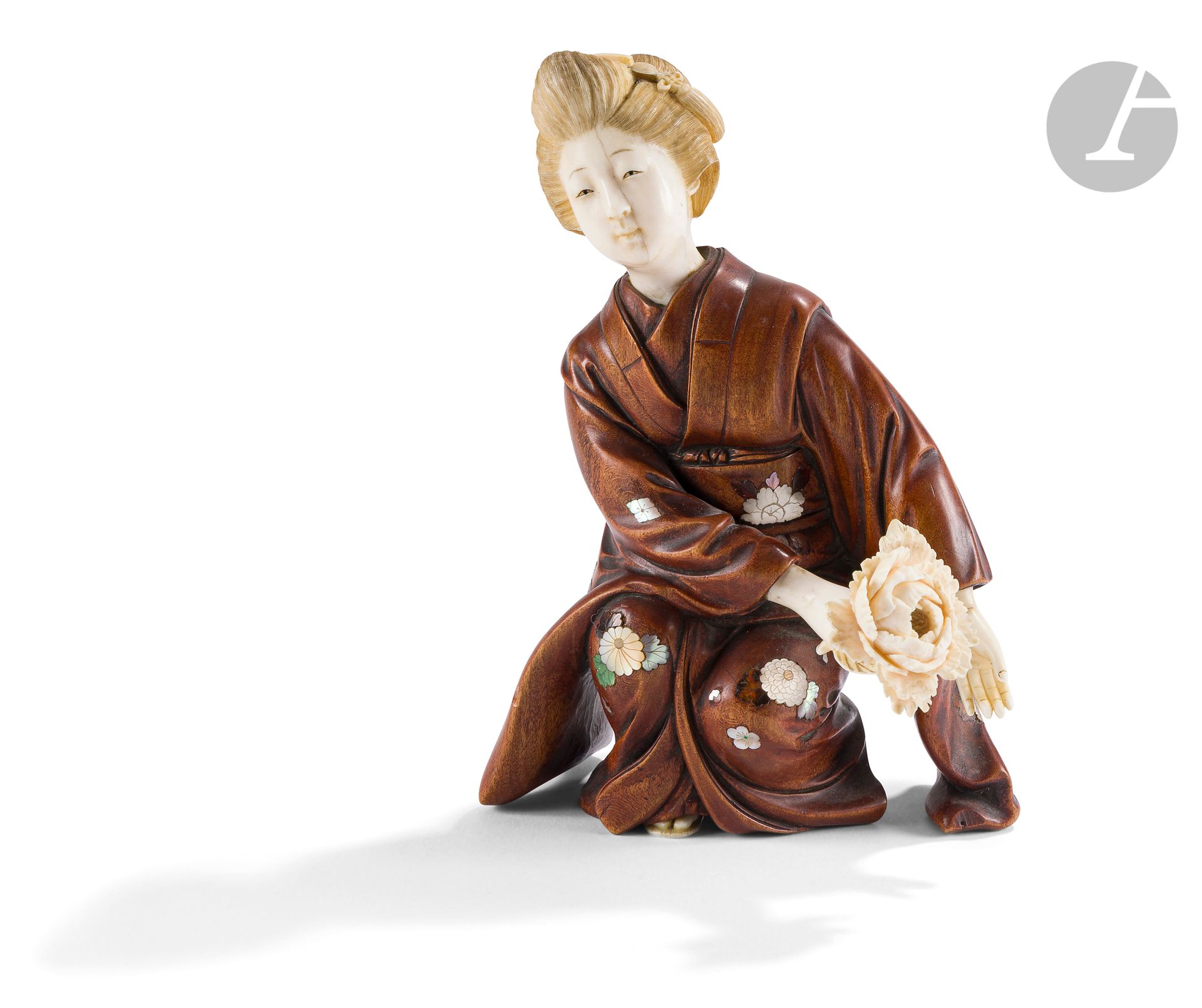 °Okimono en bois et ivoire représentant une jeune oiran, Japon, époque Meiji (1868-1912)
Représentée se préparant à prendre la position de kiza. Elle tient de la main droite une fleur de pivoine. Le kimono est en bois incrusté de nacre et d’ivoire teinté dans le style de Shibayama représentant diverses fleurs. À l’arrière, sur le bas du obi, figurent dans deux cartouches en ivoire, l’un en forme d’éventail, l’autre rectangulaire arrondi, les signatures Masayuki - 正之et Shibayama - 芝山.
Hauteur : 16,5 cm ; poids brut : 310 g
Infimes égrenures et gerce sur le visage.