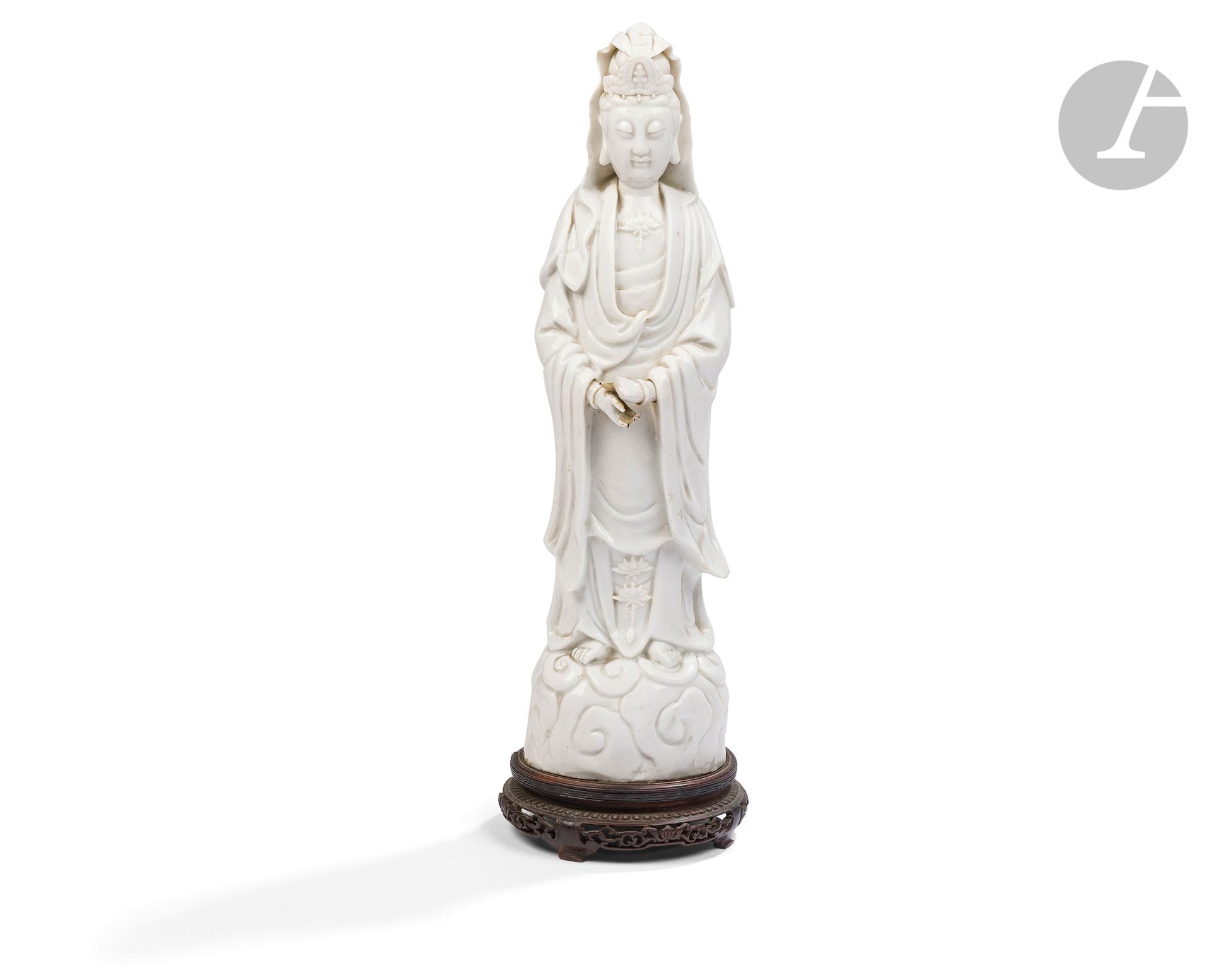 Large Chinese white porcelain Guanyin, China, Dehua, 18th century
Depicted standing on a cloud-shaped base, her face serene, eyes half-closed, a lotus flower adorns her torso. She is dressed in a robe and cloak forming harmonious folds along her body. Two lotus flowers suspended from a cord adorn the bottom of the dress. Her hair is coiffed in a bun and adorned with a tiara featuring Amitabha Buddha in the center. A veil covers the back of the head and falls to the shoulders. The urna adorns the center of the forehead. 
Height : 43 cm
Missing fingers.