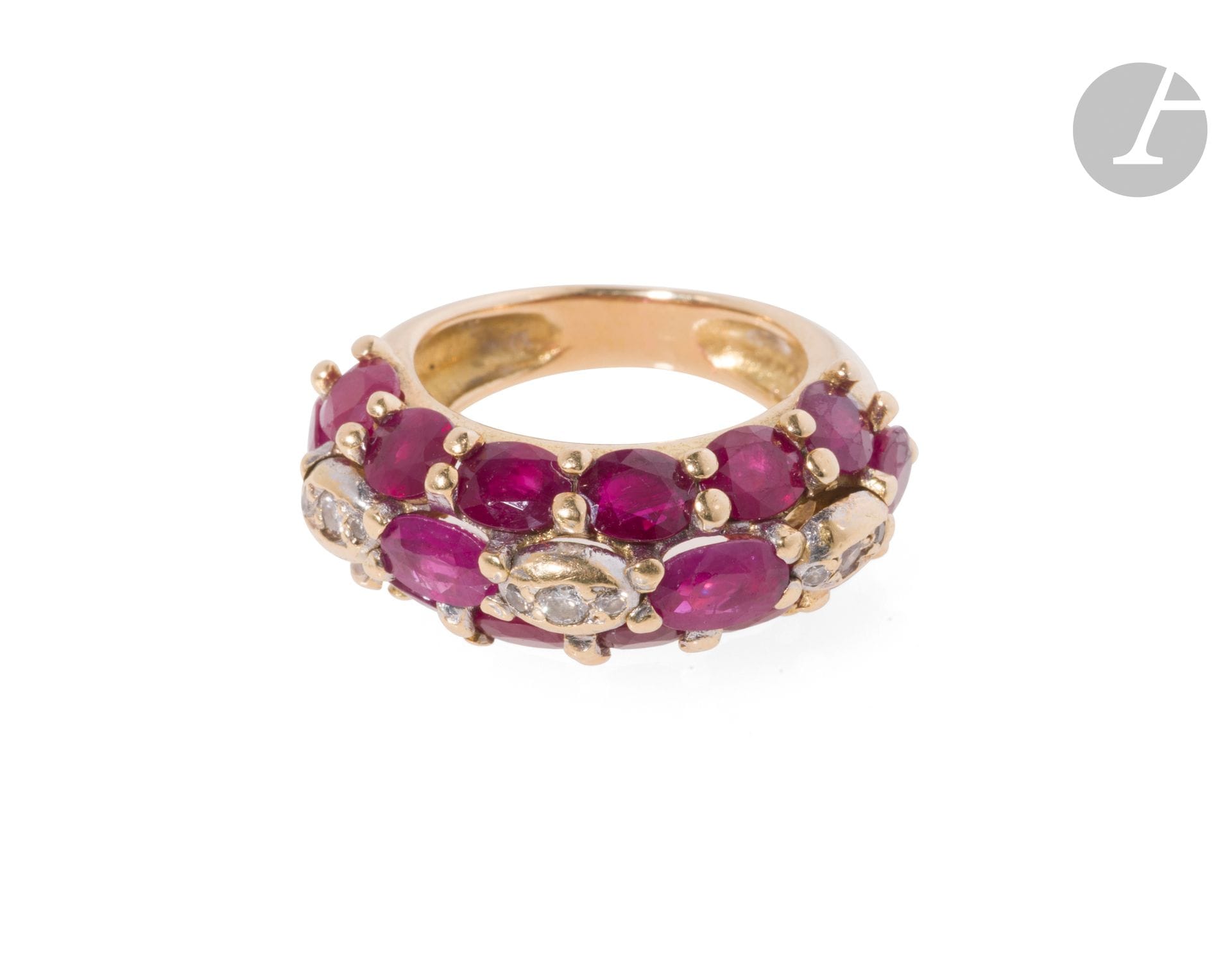 Bague en or 18K (750), sertie de trois lignes de rubis ovales, celle du milieu agrémentée de diamants de taille brillant. Tour de doigt : 53. Poids brut : 12 g (égrisures, rayures, petits chocs)