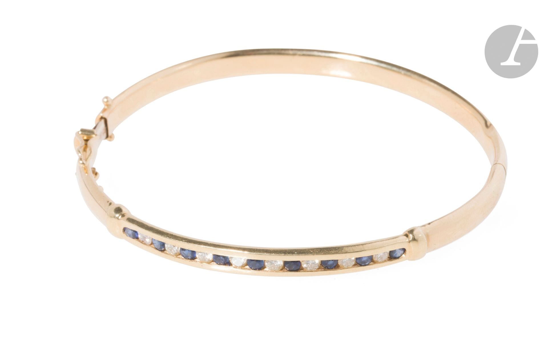 Bracelet ouvrant en or 18K (750), serti d'une ligne de diamants et de saphirs alternés. Longueur : 17,5 cm environ. Poids brut : 10,2 g (rayures, petits chocs)