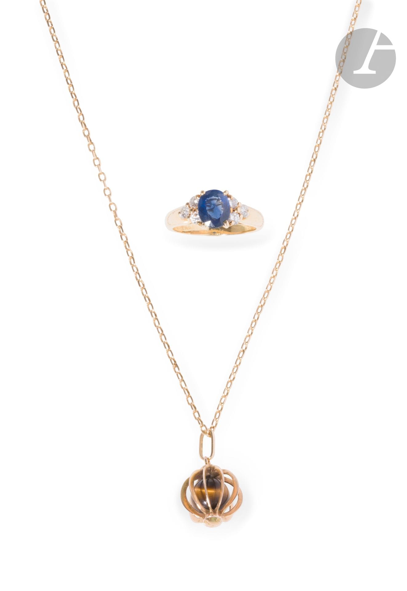 Lot de bijoux en or 18K (750) comprenant une bague sertie d'un saphir ovale épaulé de diamants ronds de taille brillant et une chaîne. Tour de doigt : 54. Poids brut : 10,1 g (on joint un pendentif en or 14K (585) retenant une bille d'œil de tigre, poids brut : 6,7 g)