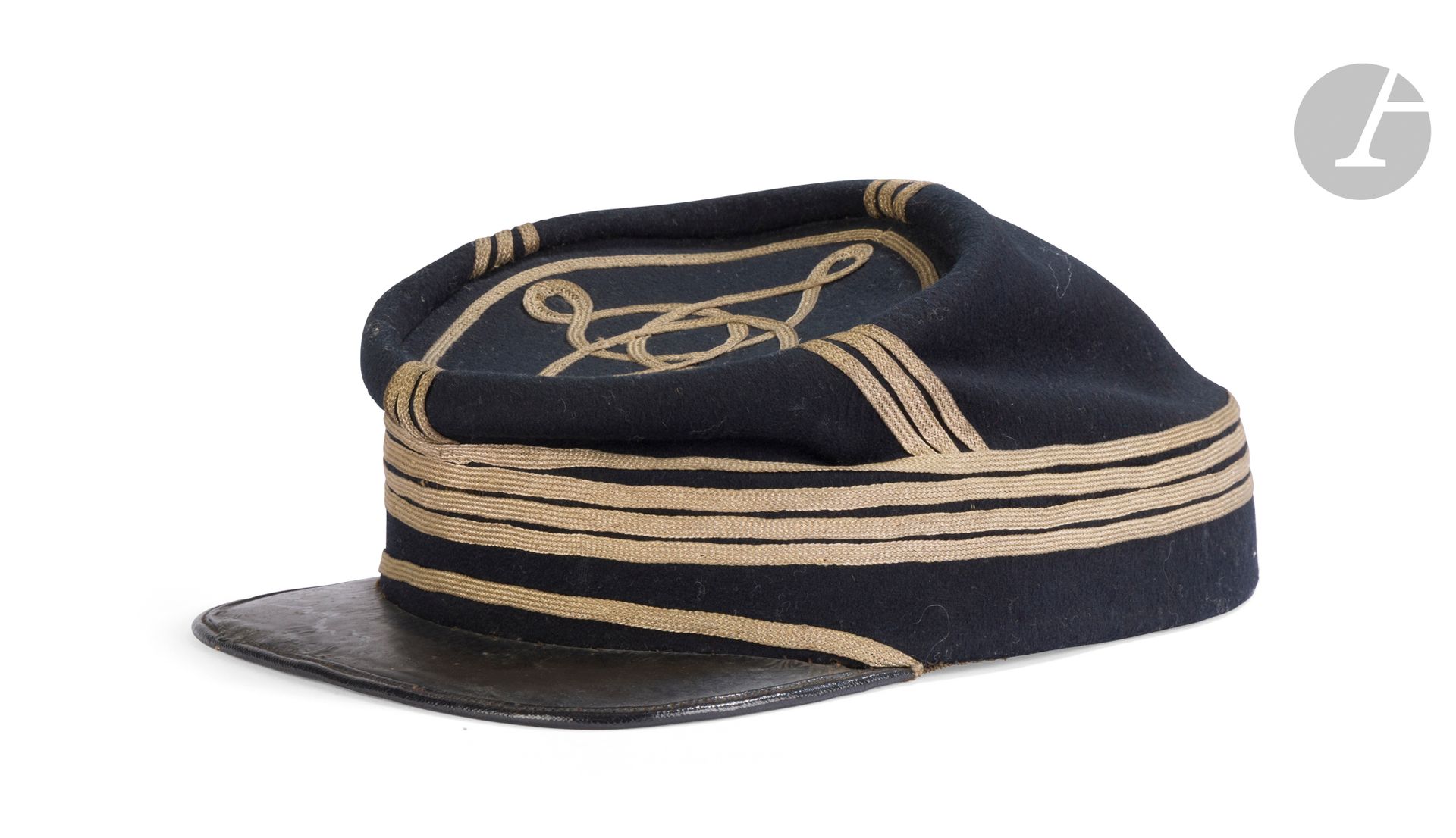 Képi de collège ou d’officier. 
Bandeau et turban en drap bleu national foncé, séparés par quatre tresses plates de grade dorées. Calotte au nœud hongrois à un seul rang de soutache plate. Fausse jugulaire en tresse plate dorée, sans boutons d’origine. Visière carrée en cuir, verni sur le dessus. Bandeau et fond de coiffe en toile enduite, avec boutons pour fixation d’une jugulaire (absente). 
B.E. (petites usures). Vers 1860-1870.