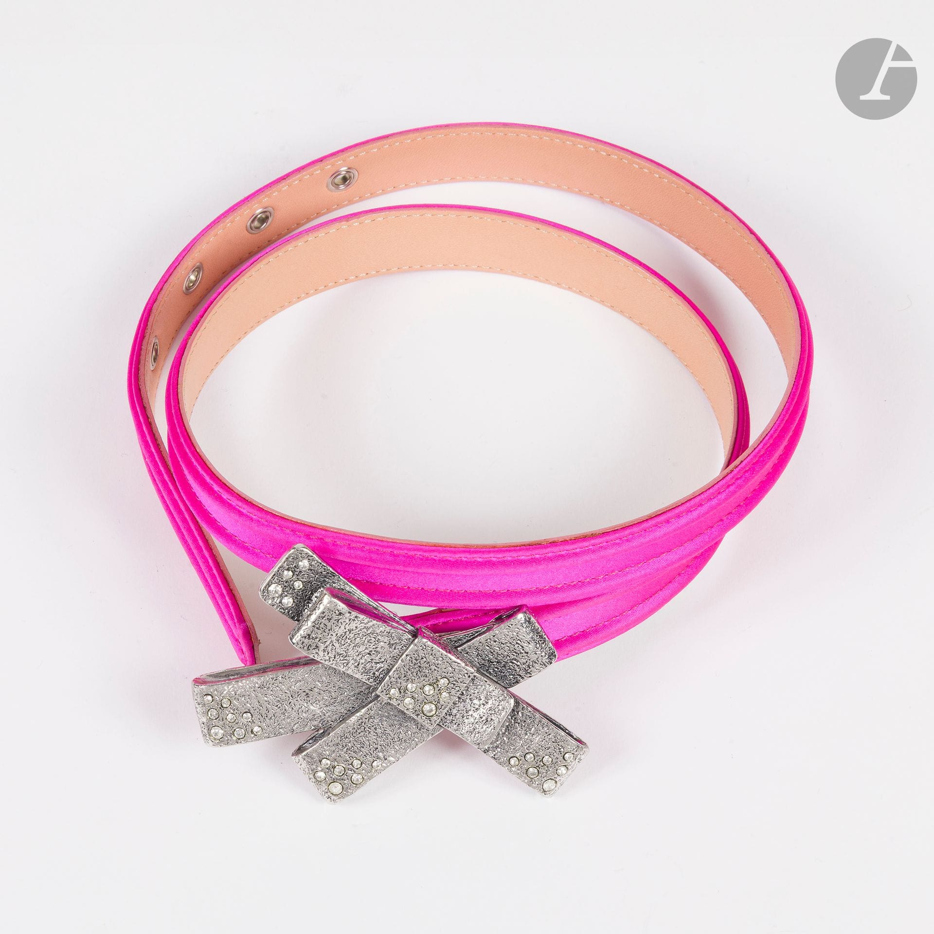 CHRISTIAN LACROIX
Ceinture en soie fuchsia rose avec boucle nœud en métal argenté incrusté de strass. T.80 environ. Dans sa boîte