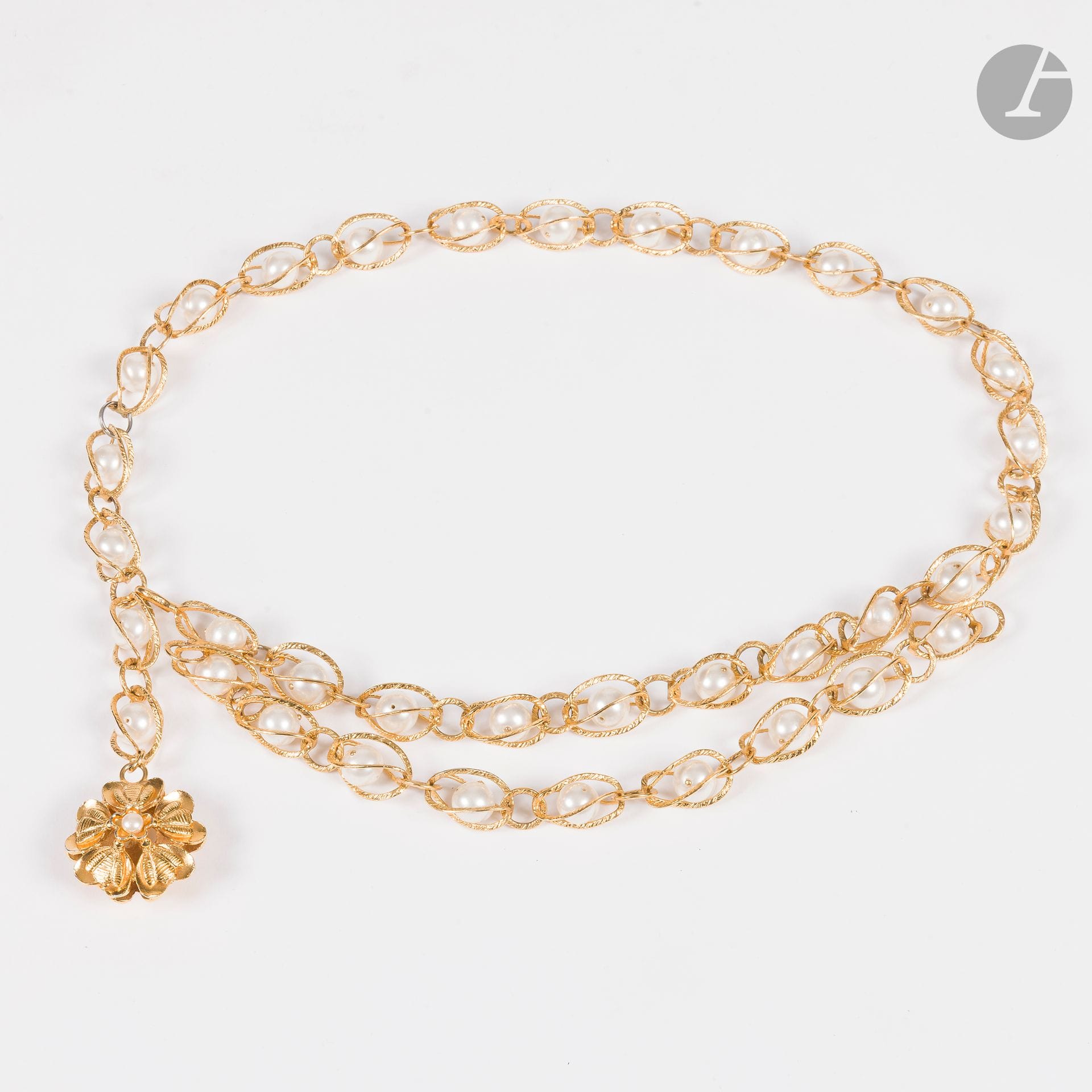 CHANEL
Ceinture en métal doré à maillons chacun retenant une perle fantaisie, élément fleur centrée d'une petite perle. Signée. T.85 environ 
(manque un petit anneau, manque la petite perle d'un coté de la boucle fleur et quelques petits éclats de nacre)