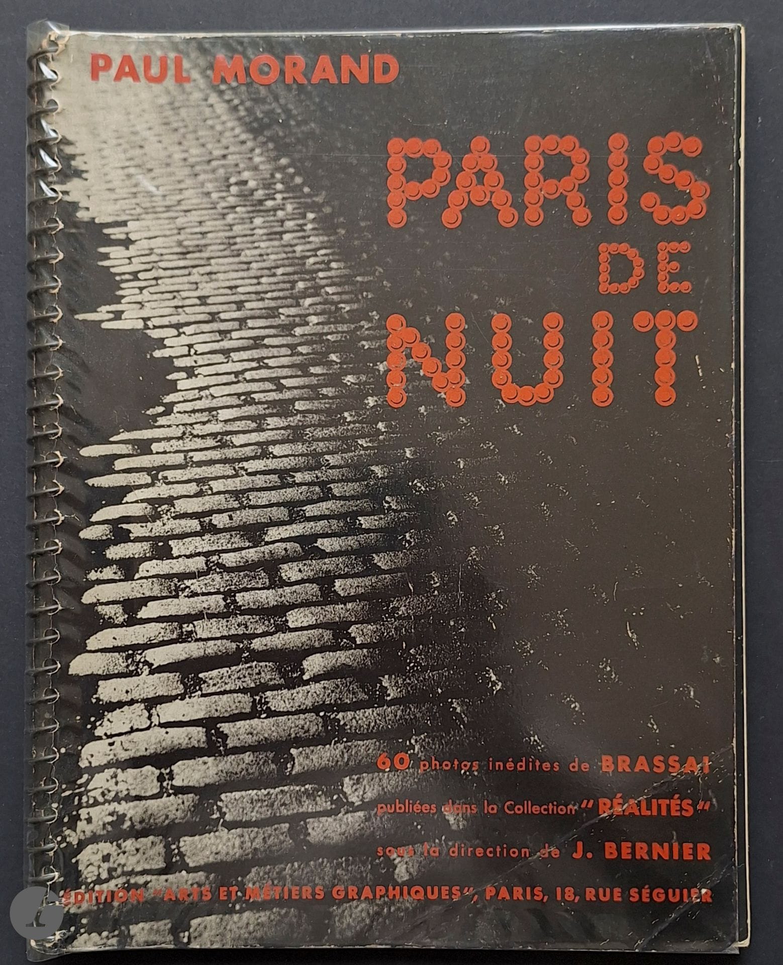 BRASSAÏ (Gyala Halasz, dit) (1899-1984)
MORAND, PAUL (1888-1976)
Paris de Nuit.
60 photos inédites de Brassaï publiées dans la collection « Réalités » sous la direction de J. Bernier.
Éditions Arts et Métiers Graphiques, Paris, 1933.
In-8 (25 x 19 cm). Édition originale. Photographies imprimées en héliogravure. Reliure à spirale. Couverture laquée, illustrée. Bel exemplaire, malgré une dédicace anonyme en page de titre.
Ref. Parr & Badger, I, p. 131 ; Hasselblad, pp. 110-111.
