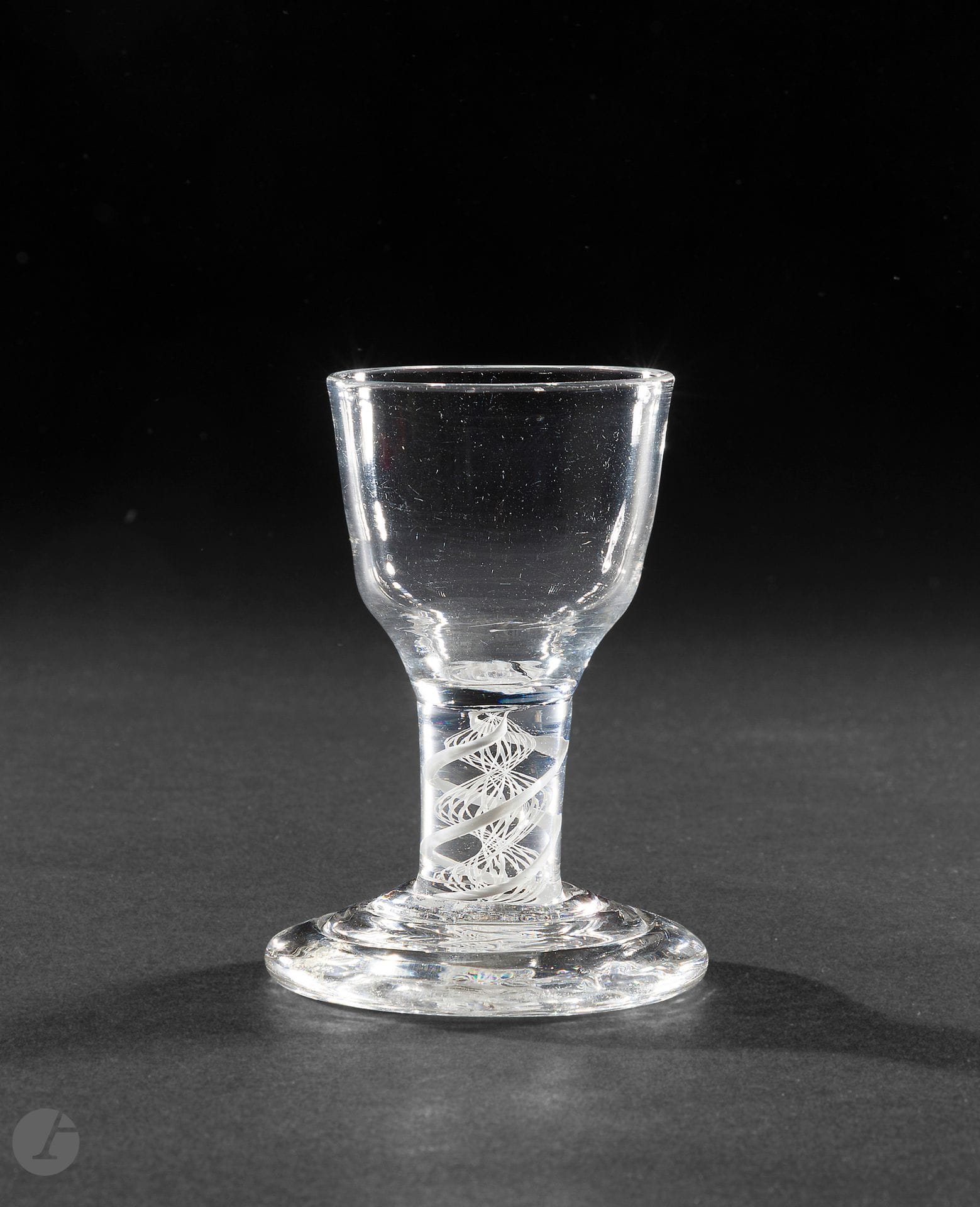 A crystal tap glass or drum glass. The ogive-shaped bowl. The leg with opaque double twist. The foot with triple circular steps. 
England, circa 1760. 
H. 9.5 cm

Provenance :
Mallett &amp; Sons 1997