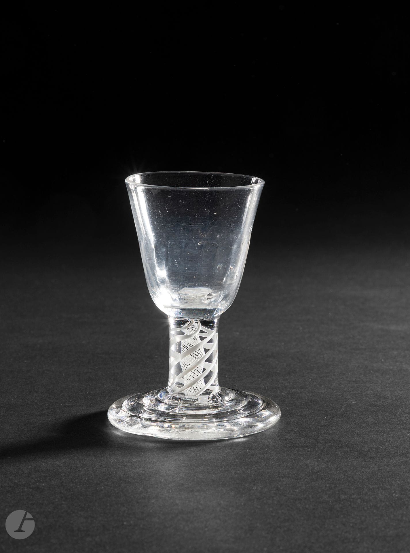 Tap glass or firing glass. The embossed cup. The leg adorned with an opaque double twist. The foot molded with concentric circles. These thick-stemmed glasses were used to tap on the table to attract attention or ask to speak at English club meetings. 
England, mid-18th century. 
H. 10 cm

Provenance :
Christopher Sheppard 1997