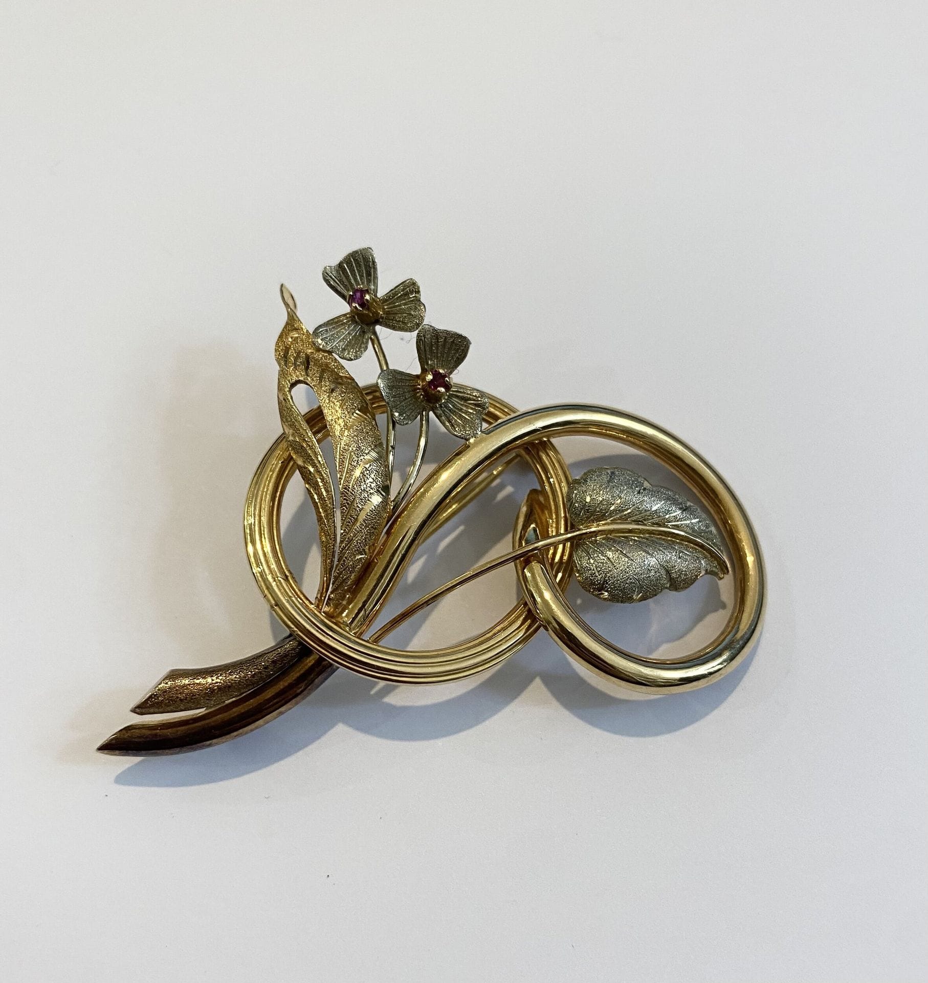 Gioielleria A. Giusta - via Roma 66 - Cuneo . Broche en or jaune et gris ciselé en forme de fleurs ornées de deux petites pierres roses. 
Poids brut. : 10,1 g