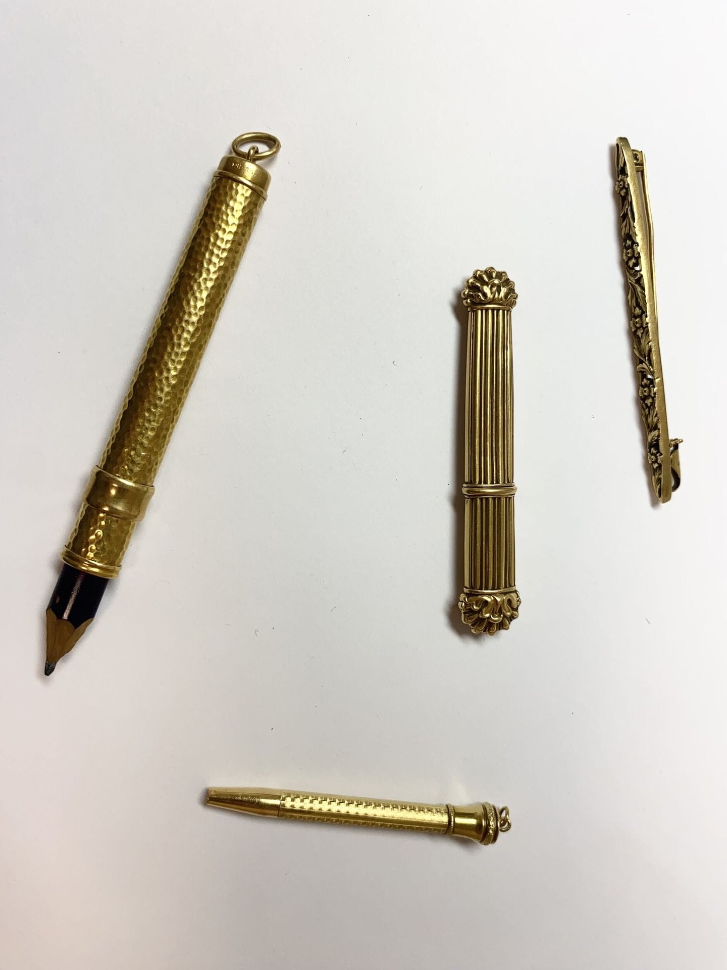 3 gold mechanical pencils and a barrette brooch in yellow gold 750/°°°. 
Two mechanical pencils and brooch with chased decoration. Net weight: 18.6 g One mechanical pencil with hammered decoration and pencil. Gross weight : 16,99