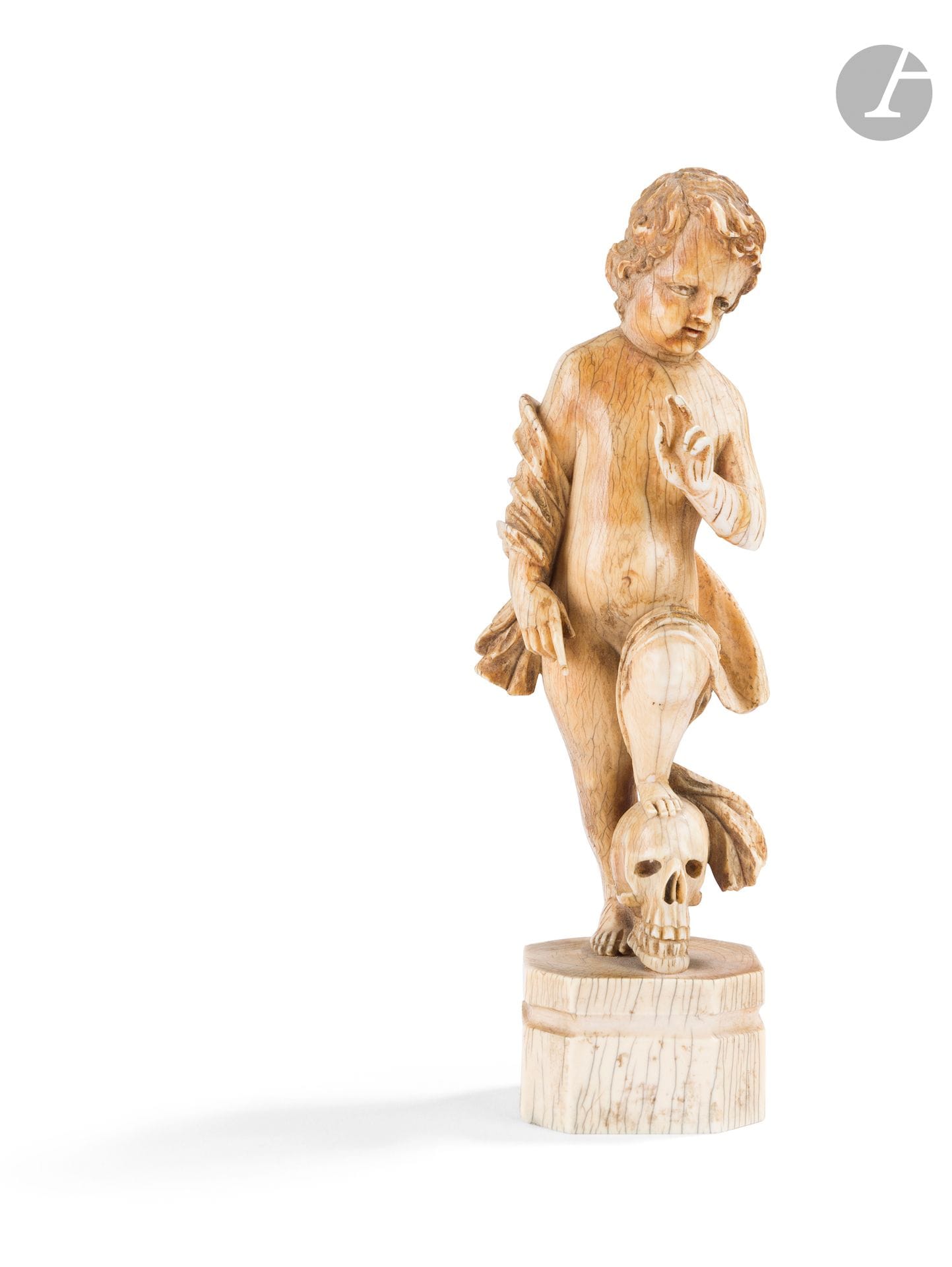 Enfant Jésus en ivoire sculpté en ronde-bosse. Debout et nu, le Christ bénissant de sa main gauche pose son pied gauche sur un crâne. Un cour manteau repose sur son avant-bras droit et passe par derrière pour se poser sur sa cuisse gauche. Soclé.
XVIIIe siècle
H. : 15,8 cm, P. : 149,6 g.