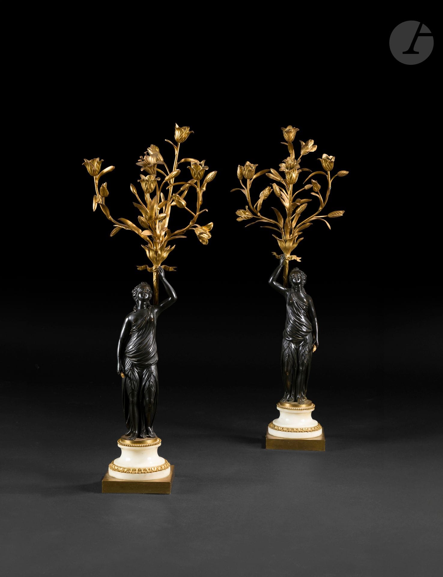 Pair of antique women's candelabra in patinated bronze and gilt bronze, with four arms of light and foliage and flower decor, the draped women's figures resting on a white marble and gilt bronze doucine base, decorated with pearl and rais-de-cœur friezes.
Louis XVI period.
H : 82 cm
MINOR CHIPS AND RESTORATIONS