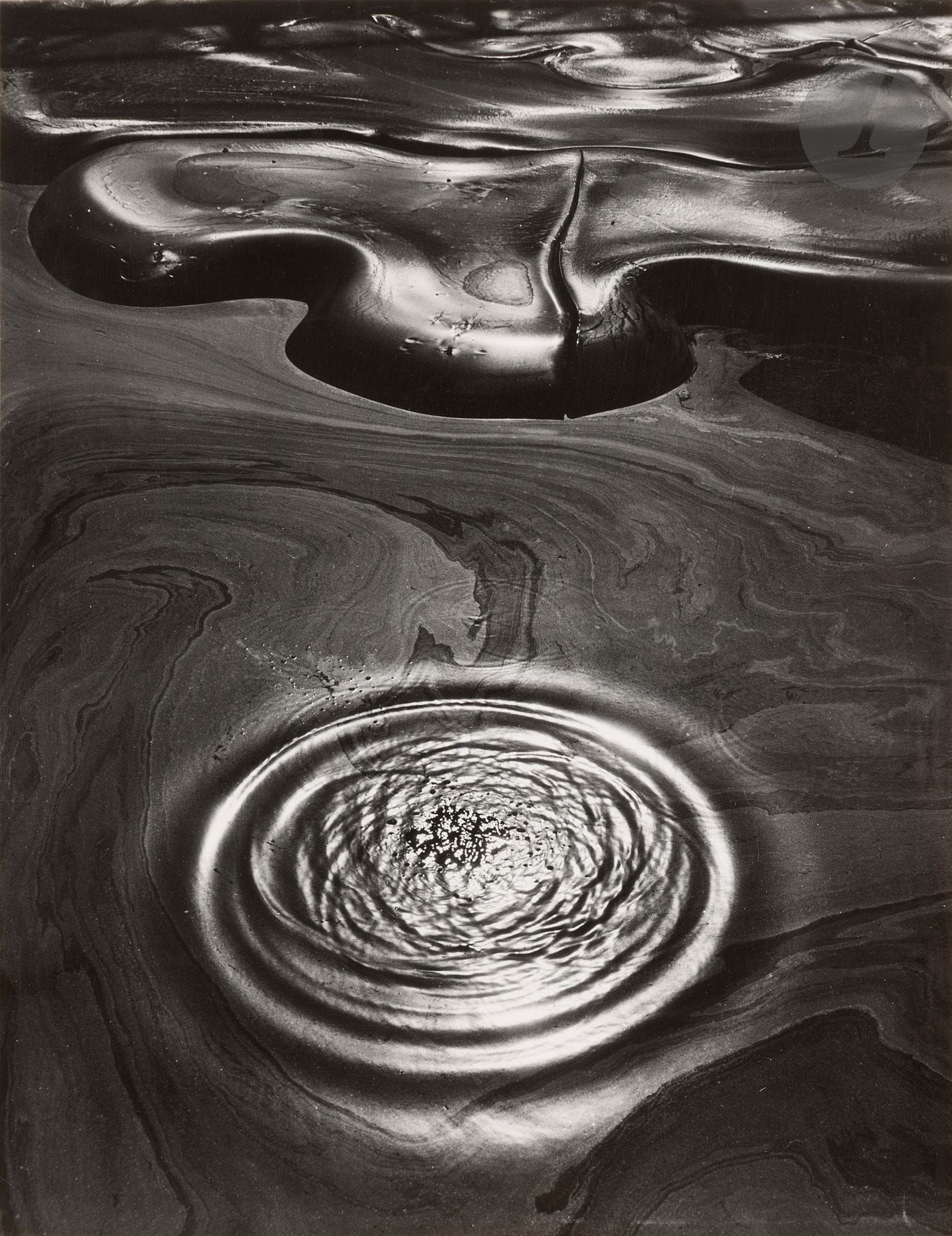 Jean Dieuzaide (1921-2003)
Les mystères du brai, 1956. 
Épreuve argentique d’époque, contrecollée sur carton et titrée à l’encre sur le montage en bas à gauche. Tampon « Reportage photographique Yan », titre, date, étiquettes de concours (Coupe de France) et de photo-clubs au verso du montage.
39,4 x 30,5 cm

Bibliographie :
Jean Dieuzaide, Mon aventure avec le brai, Toulouse, Papeteries Job [publication à compte d’auteur], 1974, couverture.

 Entre 1956 et 1958, Jean Dieuzaide poursuit un travail consacré au brai de houille, sous-produit de la cokéfaction utilisé pour la confection de briques réfractaires ou d’enduits étanches. 
À la cokerie des houillères de Carmaux, il découvre ce matériau noir et visqueux qui, une fois sec, se craquèle en réseaux géométriques. S’ouvre alors une étude au long cours de la physionomie changeante du brai, écho des mouvements intérieurs du photographe. Ce « dialogue avec un autre moi », qu’il qualifie « d’aventure », illustre la dimension réflexive et intime de l’acte photographique.