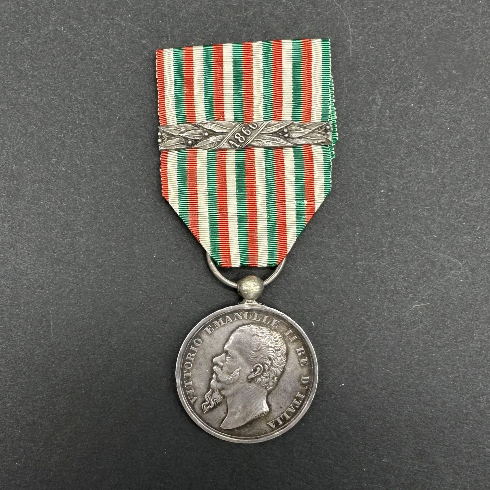 ITALIE 

Médaille de la guerre pour l’Indépendance et l’Unité de l’Italie par Ganzani (1848-1870). 

En argent, à bélière boule. Anneau cassé. Ruban ancien en soie moirée à agrafe « 1866 ». 

36 x 30 mm - Poids brut : 17,6 g

T.T.B.