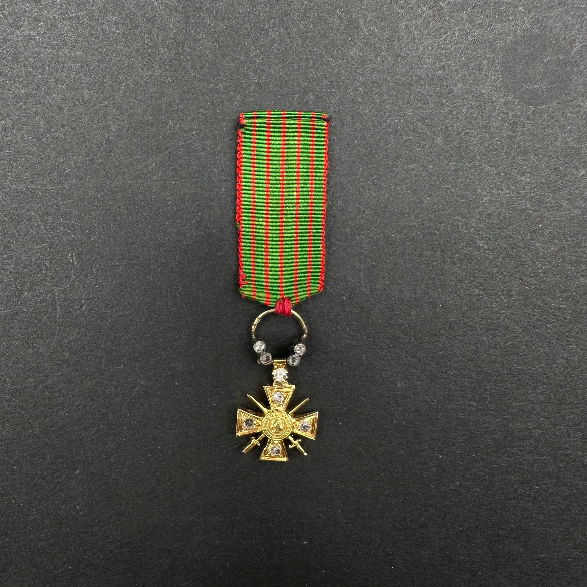 FRANCE 

Croix de guerre miniature 1914-1915, modèle de luxe, en or ciselé. Les banches et l’anneau présentant des petits diamants taillés en rose. 

Anneau doublement poinçonné tête d’aigle. Ruban d’époque cousu à l’anneau. 

26 x 13 mm (avec l’anneau) - Poids brut : 2,7 g 

T.T.B. à SUP.