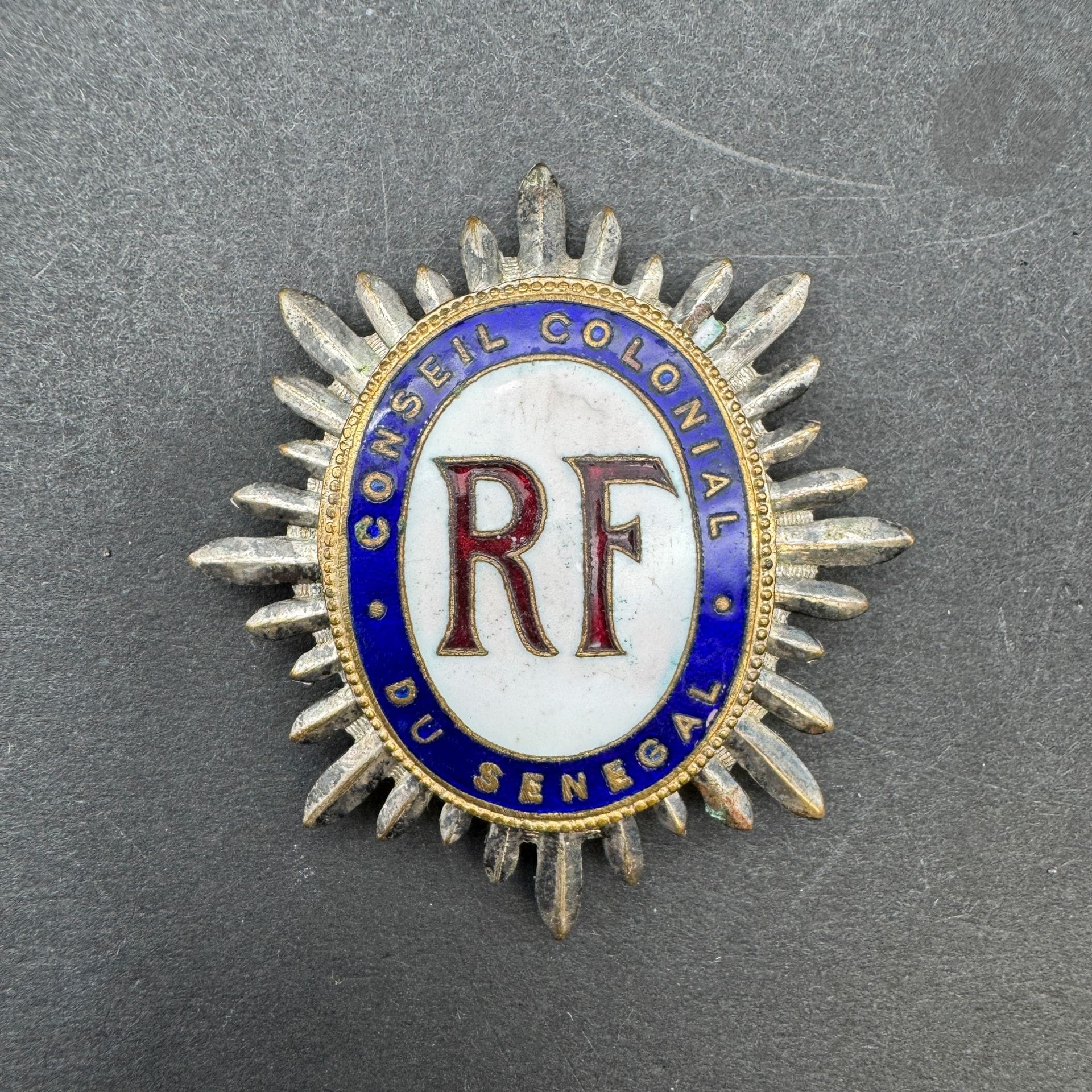 SÉNÉGAL (FRANCE) 

Insigne de conseiller du Conseil colonial du Sénégal (1920-1946). 

En métal argenté, doré et émaillé. Revers avec crochet. 

53 x 49 mm

T.T.B.