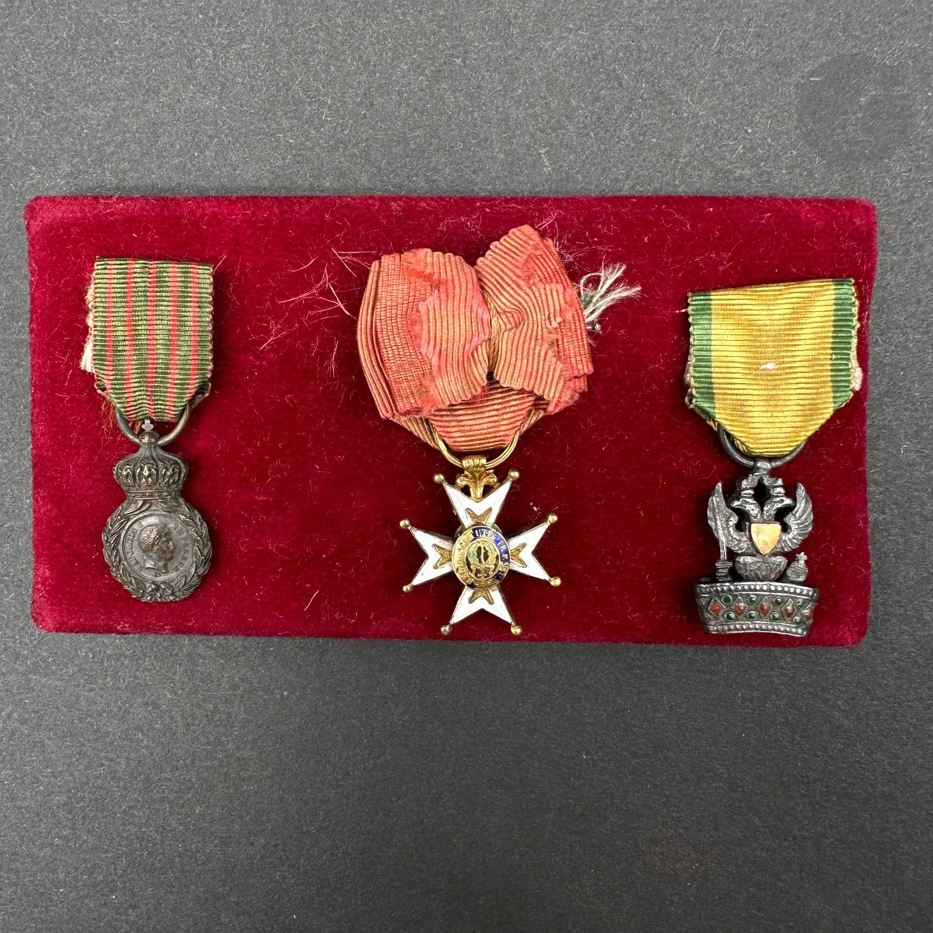 FRANCE - ORDRE DE SAINT-LOUIS

AUTRICHE - ORDRE DE LA COURONNE DE FER FRANCE - MÉDAILLE DE SAINTE-HÉLÈNE 

Groupe de trois réductions : 

- Médaille de Sainte-Hélène en bronze patiné, ruban (22 x 13 mm).

- Croix de chevalier de l’ordre de Saint-Louis en or et émail, modifiée Monarchie de Juillet (éclats aux centres), ruban à bouffette (21 x 18 mm).

- Insigne de chevalier de l’ordre de la Couronne de Fer de remplacement (Empire d’Autriche), en argent, les écus en or uni, ruban (20 x 14 mm). 

Présentées sur un support recouvert de velours pourpre. 

T.B. et T.T.B.