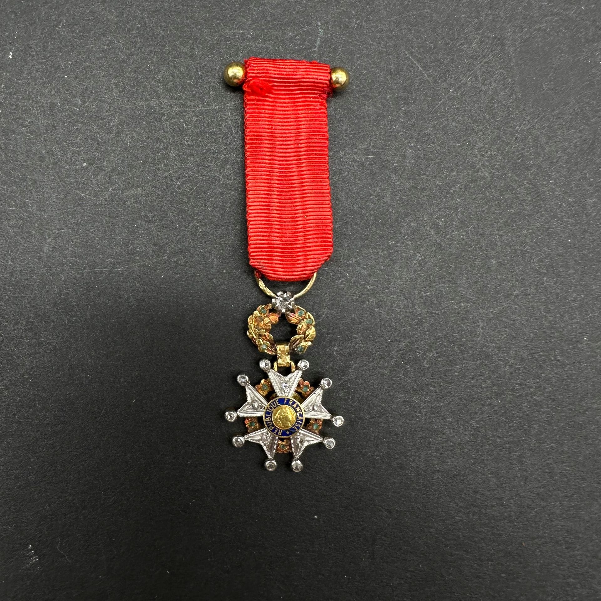 FRANCE

ORDRE DE LA LÉGION D’HONNEUR.

Belle miniature de luxe d’époque IVe République. En or, les branches doublées de platine. Couronne de feuilles de chêne et de laurier ciselé décoré d’incrustations d’émeraudes et ornée sur la bélière d’un petit diamant.

Anneau poinçonné à la tête d’aigle. Ruban.

28 x 21 mm - Poids brut : 3,5 g

SUP.