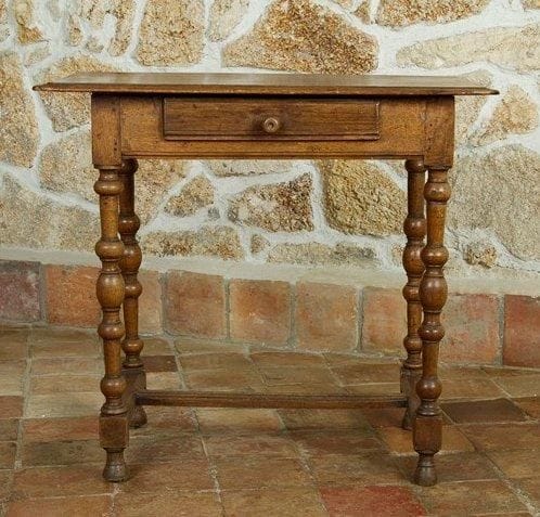 Petite table à pieds tournés d'époque Louis XIII. Elle ouvre en façade par un tiroir et elle est couverte par un plateau monoxyle mouluré; ses pieds tournés sont réunis par une entretoise en H moulurée. H.: 64 cm - L.: 71 cm - P.: 43 cm