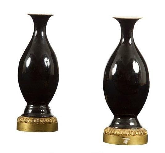 Paire de vases en porcelaine de forme balustre à fond noir et à col évasé, base en bronze ciselé à décor de godrons et fleurons. Style Louis XVI. Un col restauré. H.: 26 cm