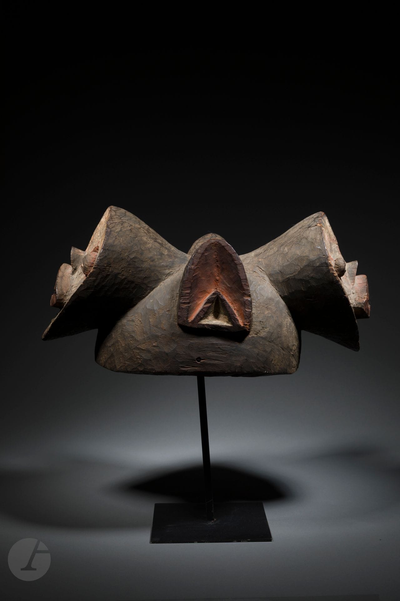 An ancient and very rare Janus helmet mask. The Mambila produced a large number of helm masks, often very expressive when they are old, but essentially zoomorphic masks with horns and very few authentic anthropomorphic face masks existed or have come down to us, and even fewer when it comes to a Janus mask. However, we can consider another authentic, early Mambila Janus mask, in a different style to the one presented here, and formerly from the American dealer J.J.Klejman (see Sotheby's NY sale of November 21, 2022 lot 44). Unfortunately, very little is known about the meaning and use of these two extremely rare masks, which make up a very narrow corpus within the Mambila culture, which has a very ancient and prolific tradition of sculpture dedicated to ancestor worship, agricultural cycles and divination. It is likely that this mask is concerned with justice or the power of perception (or divination), thanks to the clairvoyance that such sculpture enables us to see in two directions; the oldest masks in Africa always carry narrative imagery.
The Janus mask from the former Werner Muenstenberger collection, brilliantly acquired by Dieter Scharf in 1996, shows all the signs of a truly ancient work bearing the stigmata of a mask worn many times, so the quality of the carving and the striking presence of its two faces, make this work undoubtedly a truly remarkable object of Mambila artistic heritage.
Mambila, Nigeria
19th or early 20th century
Wood, pigments, small visible age-related cracks and accidents, very fine age-related oxidation of the wood, superb old patina.
Length: 42 cm

Provenance :
Dr. Werner Muensterberger Collection, New York
Collection Hilde and Dieter Scharf, Hamburg, acquired in 1996

Publications and exhibitions:
Sotheby's, New York, May 8, 1996, no. 107
Bacquart, L'Art tribal d'Afrique Noire, 1998, p. 105, no. 7
Heymer and Thompson, Sehen lernen. Eine Sammlung afrikanischer Figuren, 1999, pp. 68-69, n° 23
Rochard, Figuren Afrikas. Meisterwerke einer Privatsammlung, 2002, pp. 76-77, n° 25, Ingelheim, Altes Rathaus, April 28 - July 7, 2002