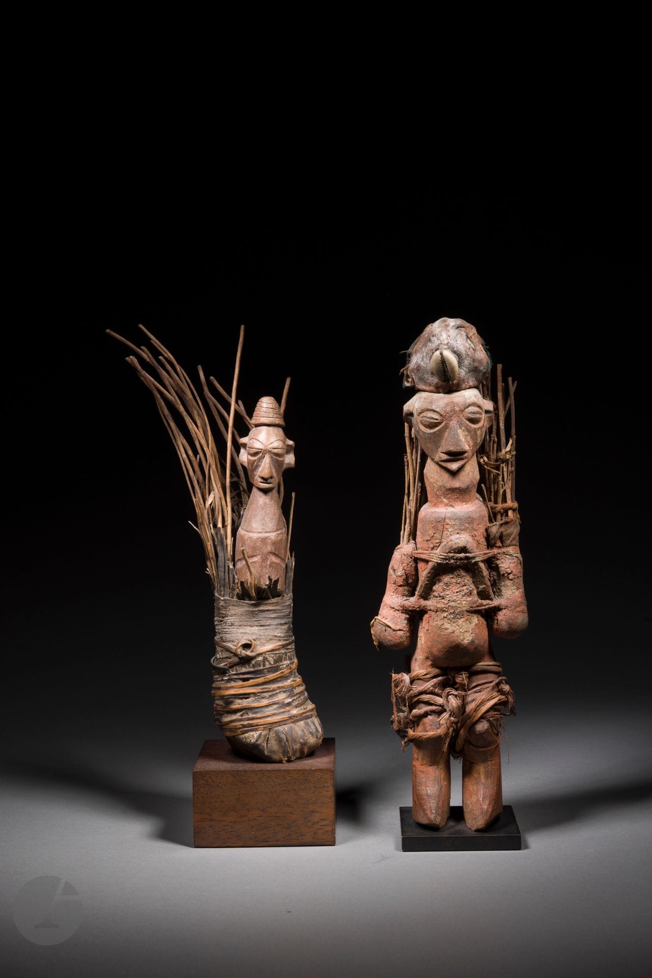 A set of two n'kisi "fetish" statuettes, generally known as biteki among the Yaka for lack of knowledge of the function and specific name of a sculpture in its original context. Loaded with magical ingredients, the biteki statuette becomes n'kisi ("medicine poison"), good or bad, which makes you sick (kukwata) or will heal and protect (kubuka).
See : Art of The Yaka and the Suku, Chaffin, p. 107
Yaka, Nigeria
Wood, ritual charge, cauri, plant fibers, ligatures, textiles, age cracks, sacrificial patina from use.
H. 21 and 29 cm

Provenance :
Stéphane Mangin / Galerie Kanaga, Paris
Collection J. Maillot, Paris, acquired 2000