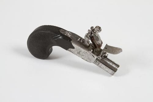 Petit pistolet à coffre à silex de Boutet.   Court canon rond, à balle forcée, gravé « Manufre à Versailles », urne fleurie et frises de fleurs et feuillages. Chien et couvre bassinet gravés en suite. Coffre gravé (usure). Détente rentrante. Crosse en ébène finement quadrillée.  B.E. Époque Consulat / Ier Empire.