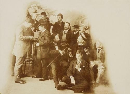 [CHAT NOIR - PHOTOGRAPHIE]. Photographie des artistes du Chat Noir. Photographie noir et blanc, 225 x 166 mm, collée sur carton avec encadrement rouge. épreuve sur papier citrate. Photographie originale des artistes du Chat Noir, vers 1890. Les artistes s'amusent autour de Salis au centre, le seul à regarder l'objectif. En haut de la photographie on peut lire cette légende manuscrite de l'époque: "Albert ? payant les artistes du Chat- Noir et paie Jules Jouy"