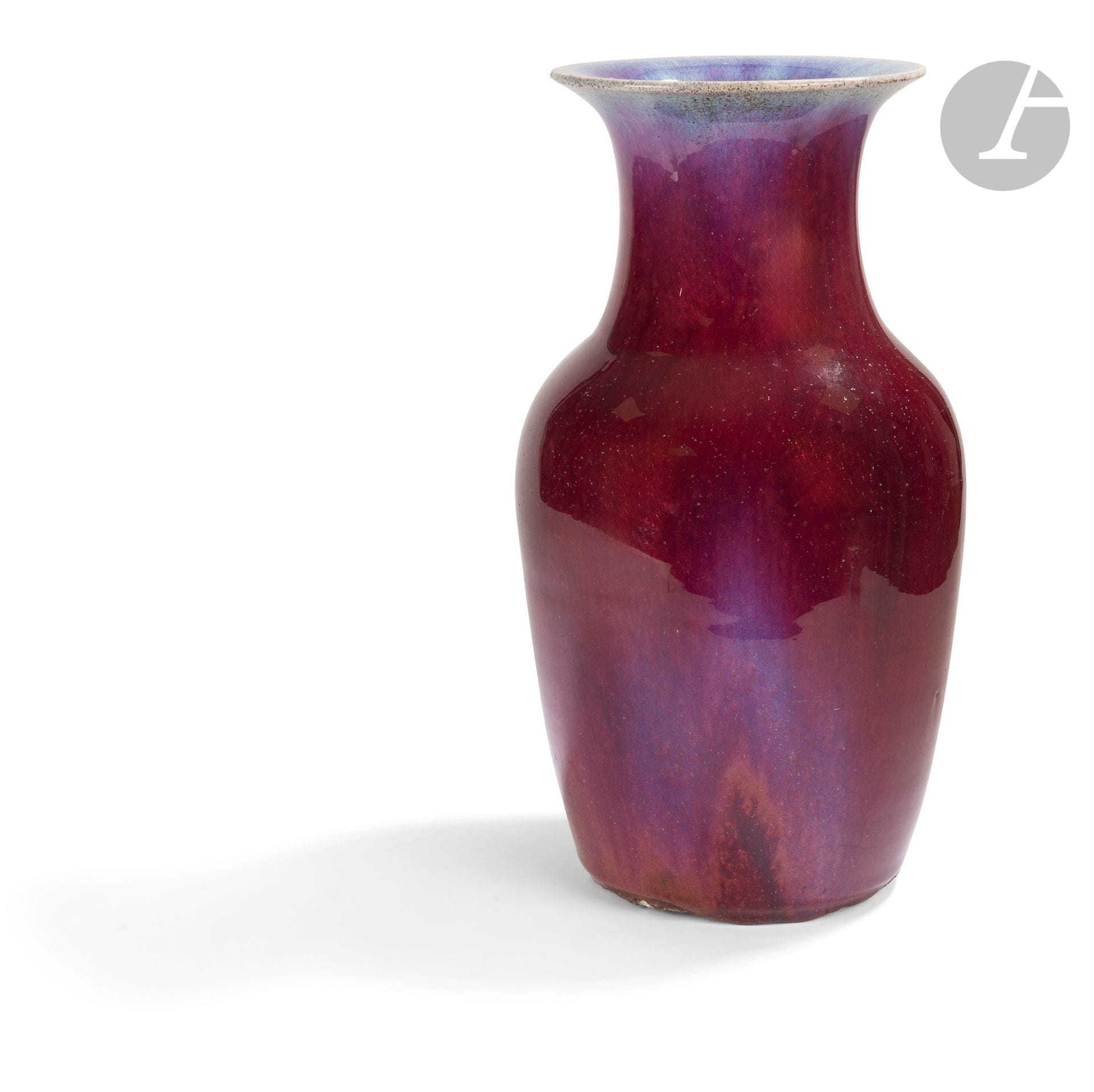 Vase balustre en porcelaine sang de bœuf, Chine, XXe siècle
Le vase est recouvert d’une glaçure de couleur rouge appelée « sang de bœuf », montrant des nuances bleutées dites flammées sur certaines parties de la panse, en haut et à l’intérieur du col évasé. Le talon est partiellement couvert par des coulures d’émail et volontairement cassé à certains endroits pour stabiliser le vase. Le fond n’est pas émaillé.
Hauteur : 38 cm