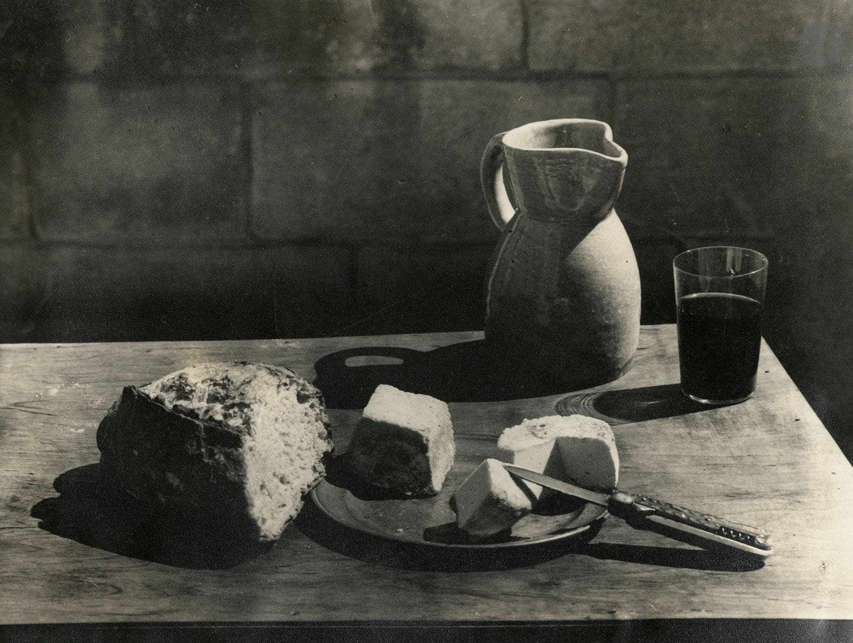 Juan Ruiz de Luna (1863-1945) 
Nature morte [pain, fromage et cruche], c. 1930. 
Épreuve argentique d'époque, contrecollée sur carton. Signature du photographe au crayon sur le montage. 
22,5 x 29,5 cm