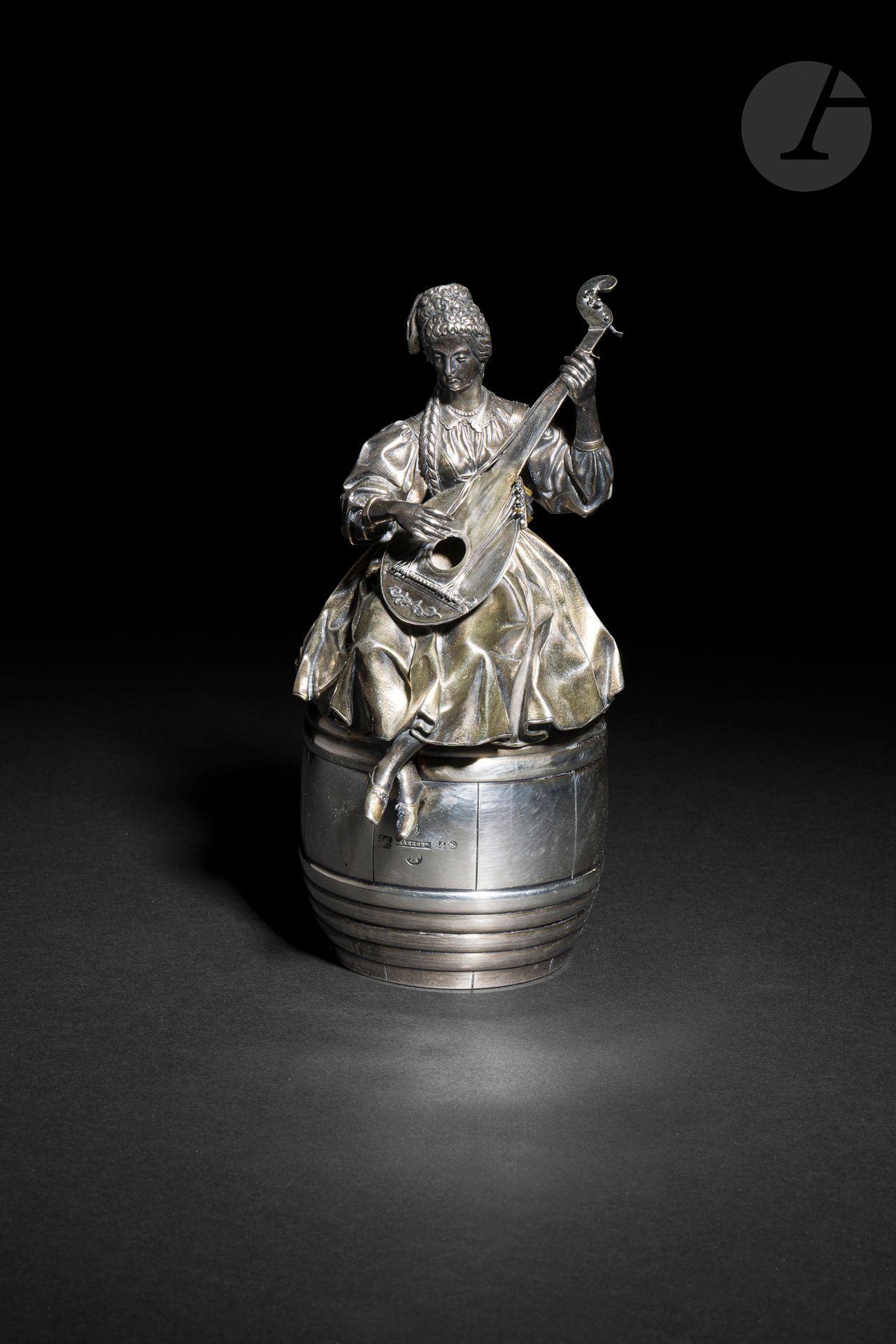 Ignaty Pavlovitch SAZIKOV (1796-1868)
Казачка, играющая на бандуре (femme cosaque jouant de la bandoura)
La femme est assise sur un tonneau faisant office de gobelet à vin.
Ce modèle a été créé en 1850-1851 avec la femme cosaque assise sur un baquet. C’était l’une des réalisations parmi la trentaine présentées par Sazikov à l’Exposition Universelle de Londres, dans la lignée des statuettes représentant les types de Russie en porcelaine de Gardner des années 1820 (mais Sazikov ajoute une dimension utilitaire (presse-papier, gobelet, pichet).
Le sujet a été repris par I. P. Sazikov comme en témoigne le poinçon qui date d’avant sa mort en 1868, mais avec certaines variantes. Il est difficile de comparer, la seule représentation connue est une lithographie du journal « Русский художественный листок » (La feuille d’art russe) de 1851, n°13. Il n’est pas exclu que ce soit un remontage de l’original sur un tonneau à la place du baquet par la firme Sazikov peu après le décès de I. P. Sazikov.
La statuette est en argent, la robe et les souliers sont vermeillés, ainsi que (du moins en partie) la bandoura. Le tonneau en argent est doré à l’intérieur.
La statuette est maintenue sur le tonneau grâce à deux petites goupilles cachées dans les plis de la robe.
Poinçons de la sculpture : 84, Saint-Pétersbourg et orfèvre « ИС » (Ignaty Pavlovitch Sazikov).
Poinçons du tonneau : 84, Saint-Pétersbourg 1870, essayeur « ИЕ » (Ivan Vonifatievitch Evsigueneev) et orfèvre « САЗИКОВЪ » (Firme Sazikov) avec l’aigle de fournisseur à la Cour et la médaille de l’Exposition Universelle de Londres en 1851 avec les profils de la reine Victoria et du prince Albert.
Hauteur : 19,5 cm ; diam. du tonneau : 8,9 cm ; poids brut : 969 g

[art russe]