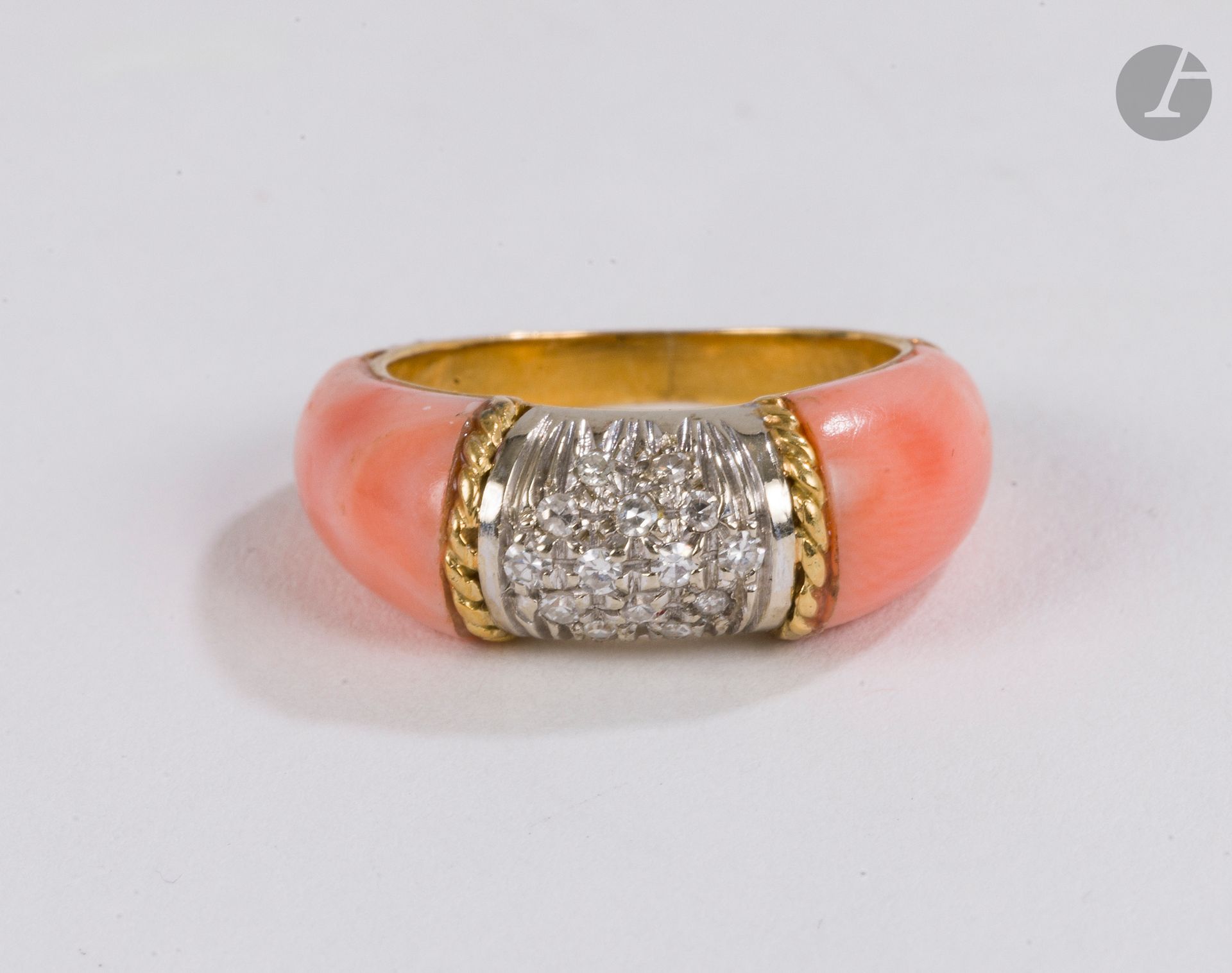 Bague en or 18K (750), sertie de diamants ronds de taille brillant épaulés de corail rose. Tour de doigt : 50. Poids brut : 5.5 g (rayures, micro chocs, traces de colle)