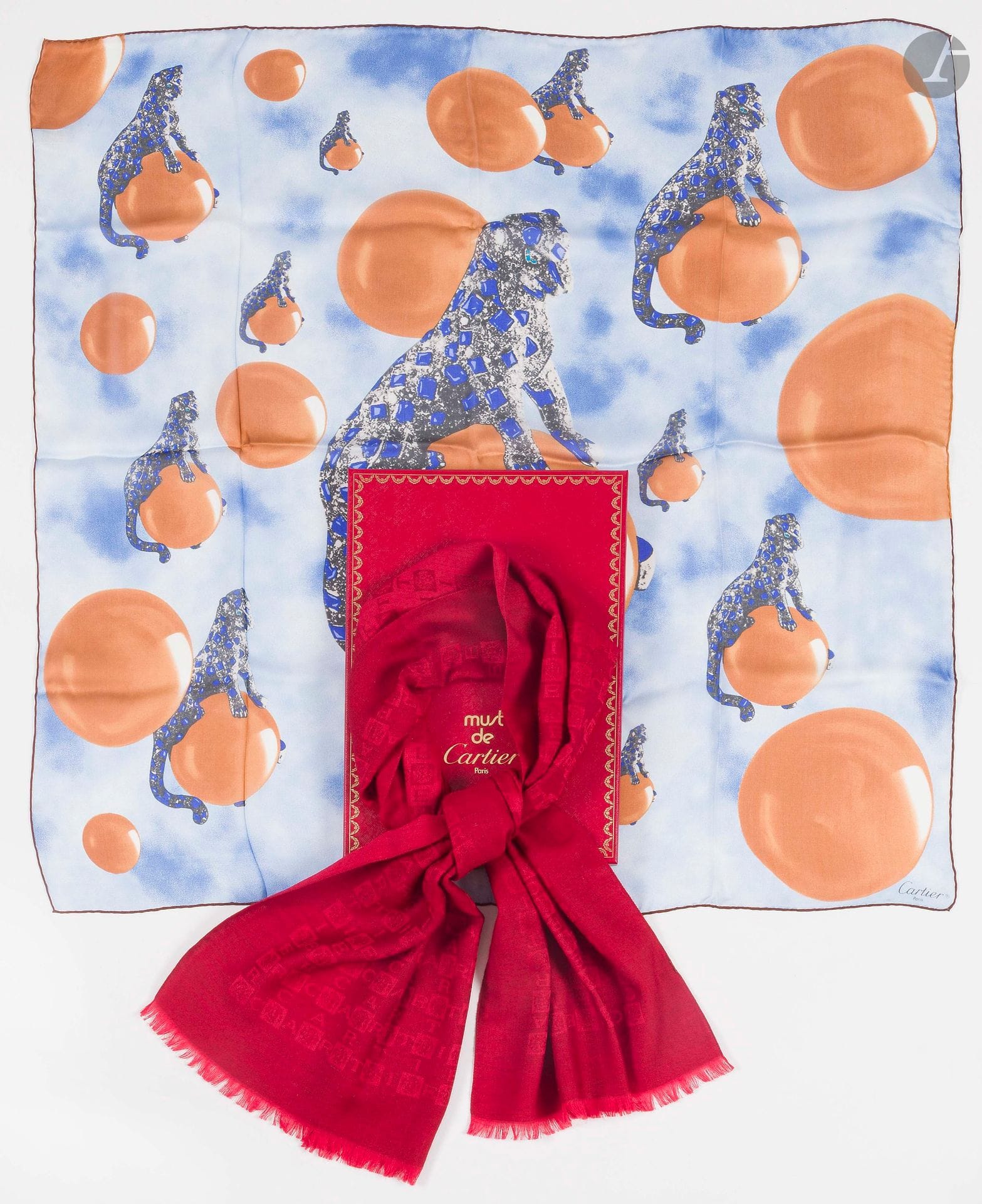 MUST DE CARTIER
Trois pièces dans leur boîte : 
- un foulard bijoux en twill de soie dans les tons rouges. 66 x 66 cm
- un foulard panthère en mousseline de soie dans les tons camel et bleus. 87 x 87 cm
- écharpe en cachemire rouge damassé à décor Cartier. 155 x 45 cm