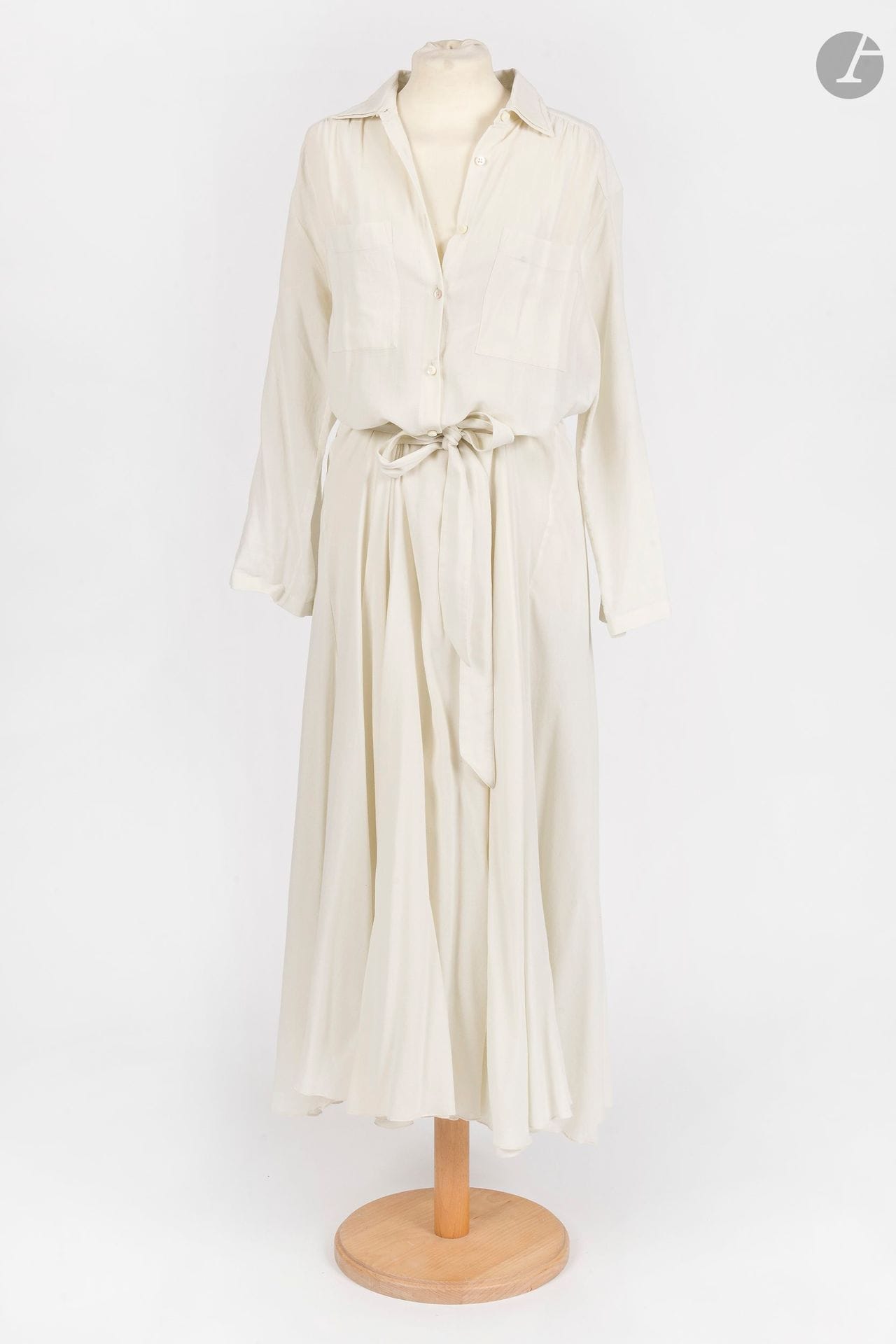 MAISON MARTIN MARGIELA Ligne 4
Robe longue chemise en crêpe de coton crème, double col et manches pouvant se boutonner, avec sa ceinture et son fond de robe. T.40 indiquée (rares fils tirés, petit accroc à l'épaule droite)