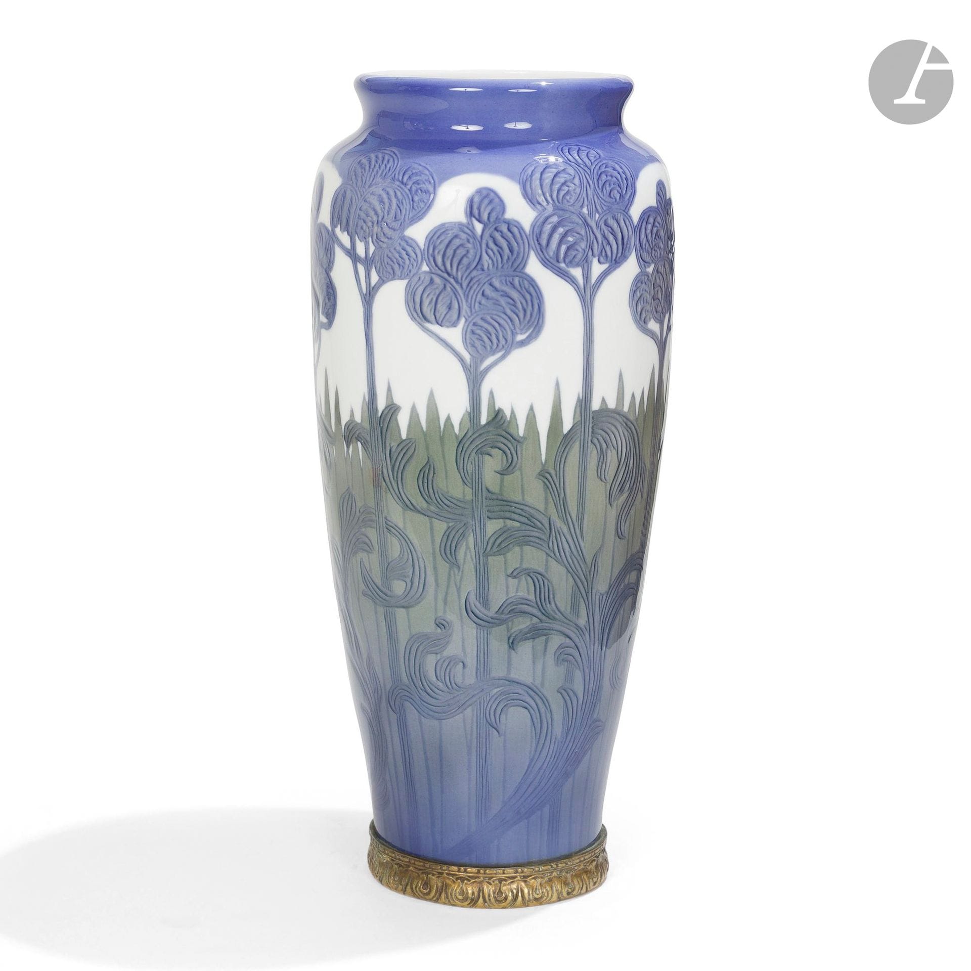 ROYAL COPENHAGEN
Rêve floral
Très haut vase balustre à col annulaire ; la base en bronze aux motifs géométriques dans le goût de l’Art nouveau scandinave. Épreuve en porcelaine émaillée ; le décor traité dans un camaïeu bleuet en léger relief sur fond blanc. La marque non accessible du fait de la monture en bronze. H.44 cm  

Bibliographie et œuvres en rapport : 
- Elliot Todd – Danish Porcelain : 250 Years of Royal Copenhagen and Bing & Grøndahl – Volume I – Éditions ACC Art Books, Woodbridge, 2025. Des modèles de forme identique, à variante de décors, reproduits pages 261 et 274. 
- Elliot Todd – Danish Porcelain : 250 Years of Royal Copenhagen and Bing & Grøndahl – Volume II – Éditions ACC Art Books, Woodbridge, 2025. Un modèle de forme identique, à variante de décor, reproduit page 91.