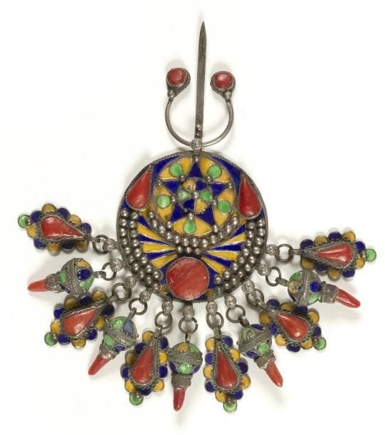 Fibule ronde, tabzimt, Algérie, Grande Kabylie, Benni Yenni, XXe siècle Argent émaillé en polychromie et cabochons de corail, à décor d?une étoile bordée d?un croissant de lune, et ceinte d?une couronne perlée. Pendeloques en boule et en amande également émaillées en polychromie et serties de cabochons de corail. H.: 14 cm A round fibula, Tabzimt, Algeria, Great Kabylia, Benni Yenni, 20th century